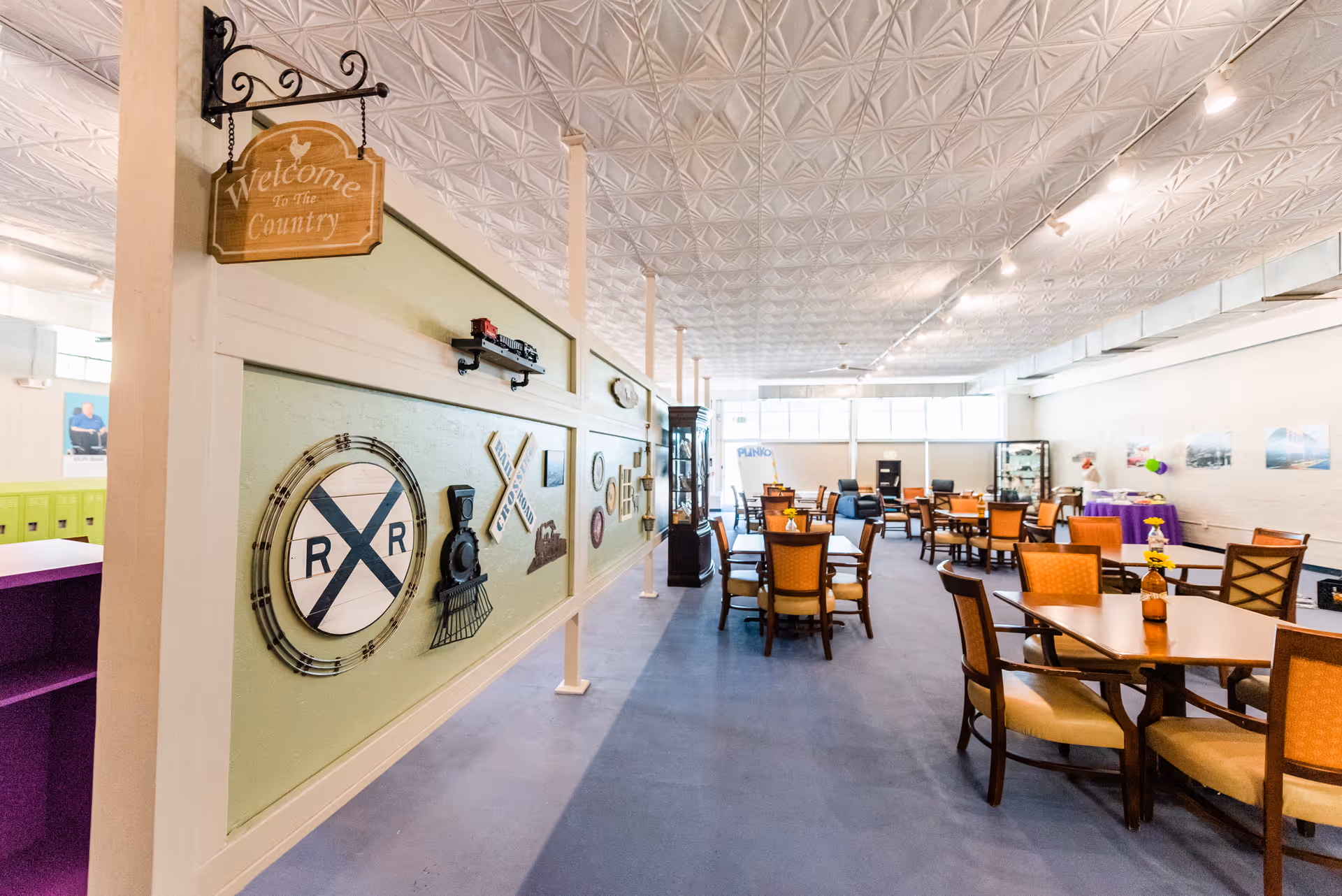 Interior dining area with multiple tables and chairs, decorative wall features, and ceiling lighting.