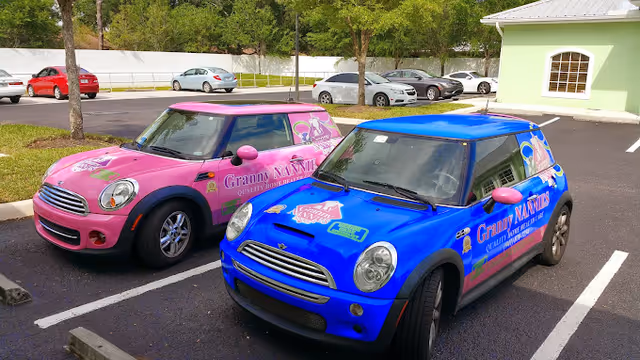 Two colorful Granny Nannies-branded cars parked in a lot near a lime-green building.