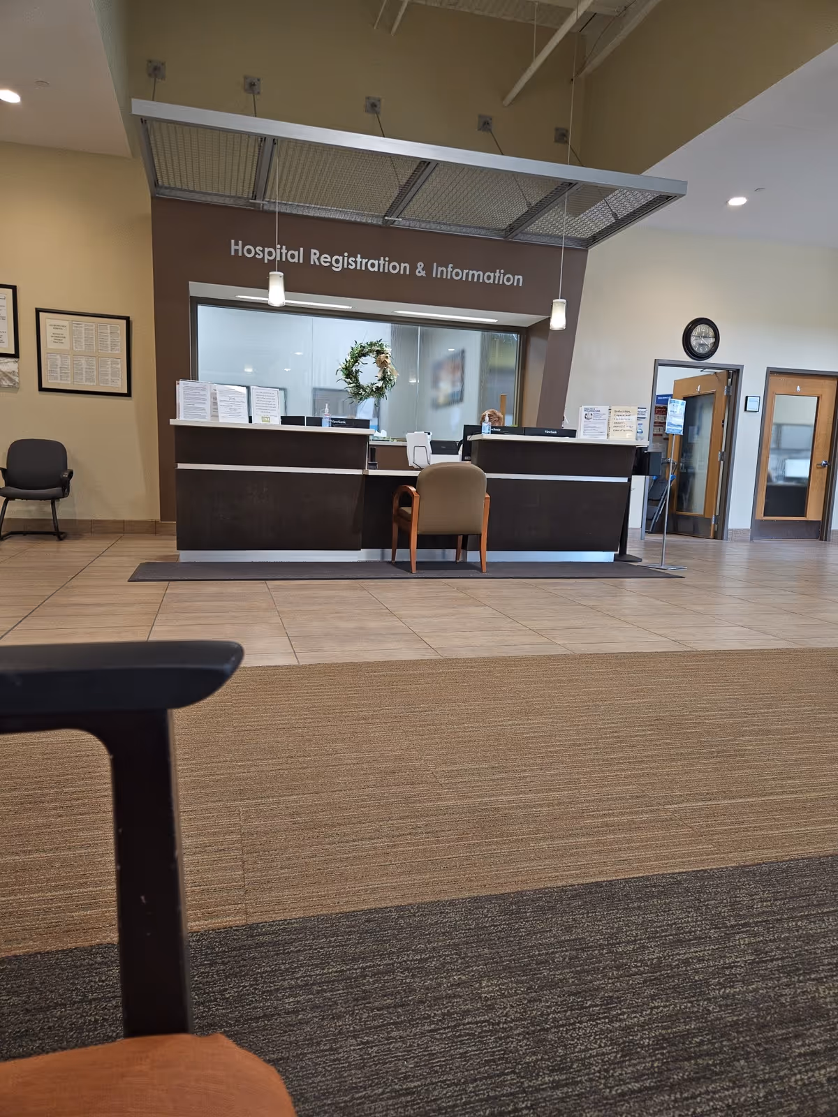 Hospital registration desk inside a spacious lobby with seating and a wreath decoration.