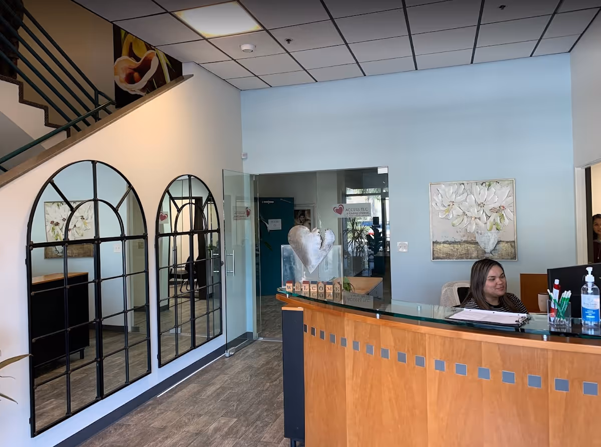 Bright Access TLC lobby with a reception desk, glass doors, decorative arches, and wall art.