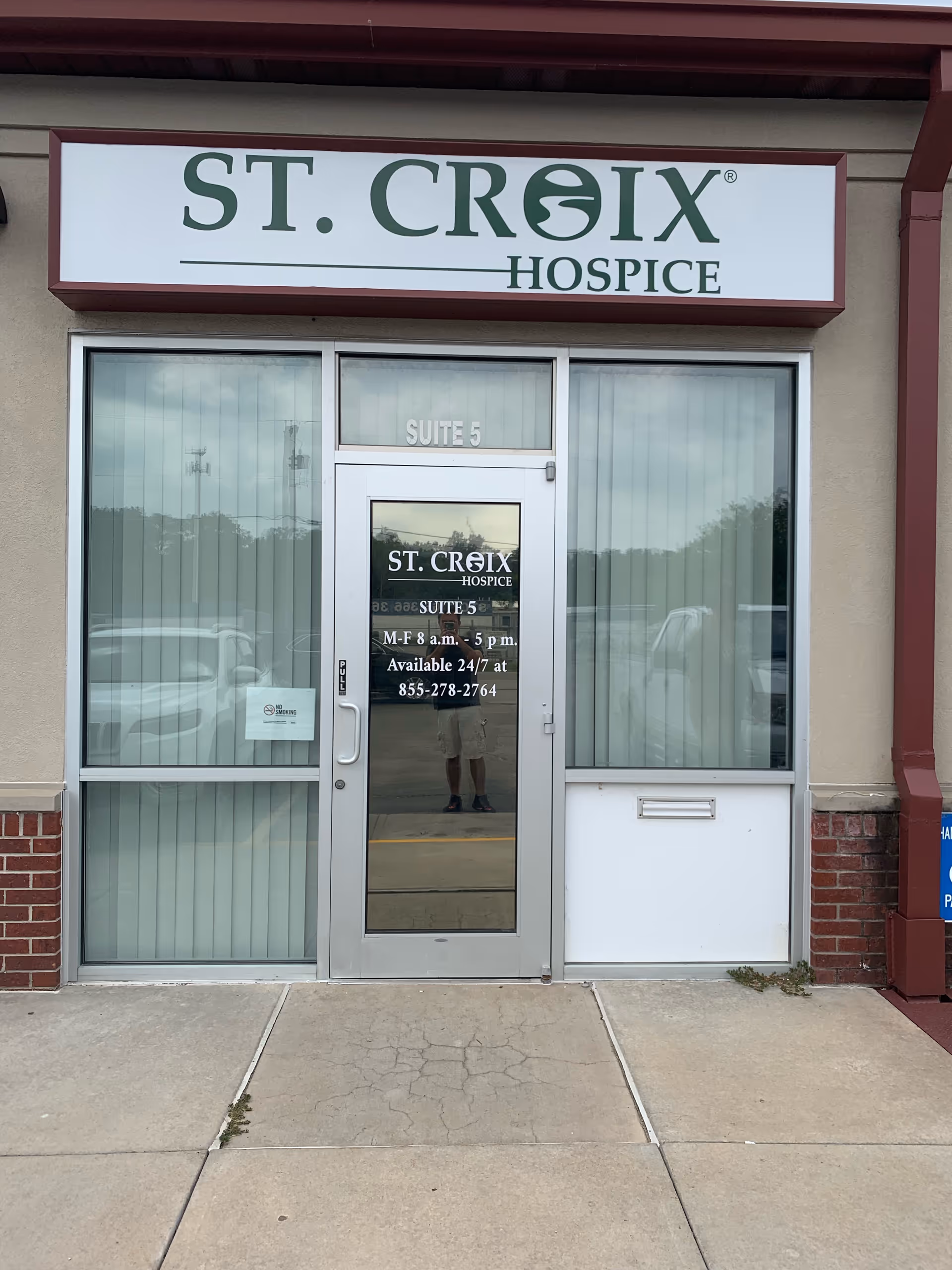 Exterior of St. Croix Hospice entrance with glass door and large sign above.