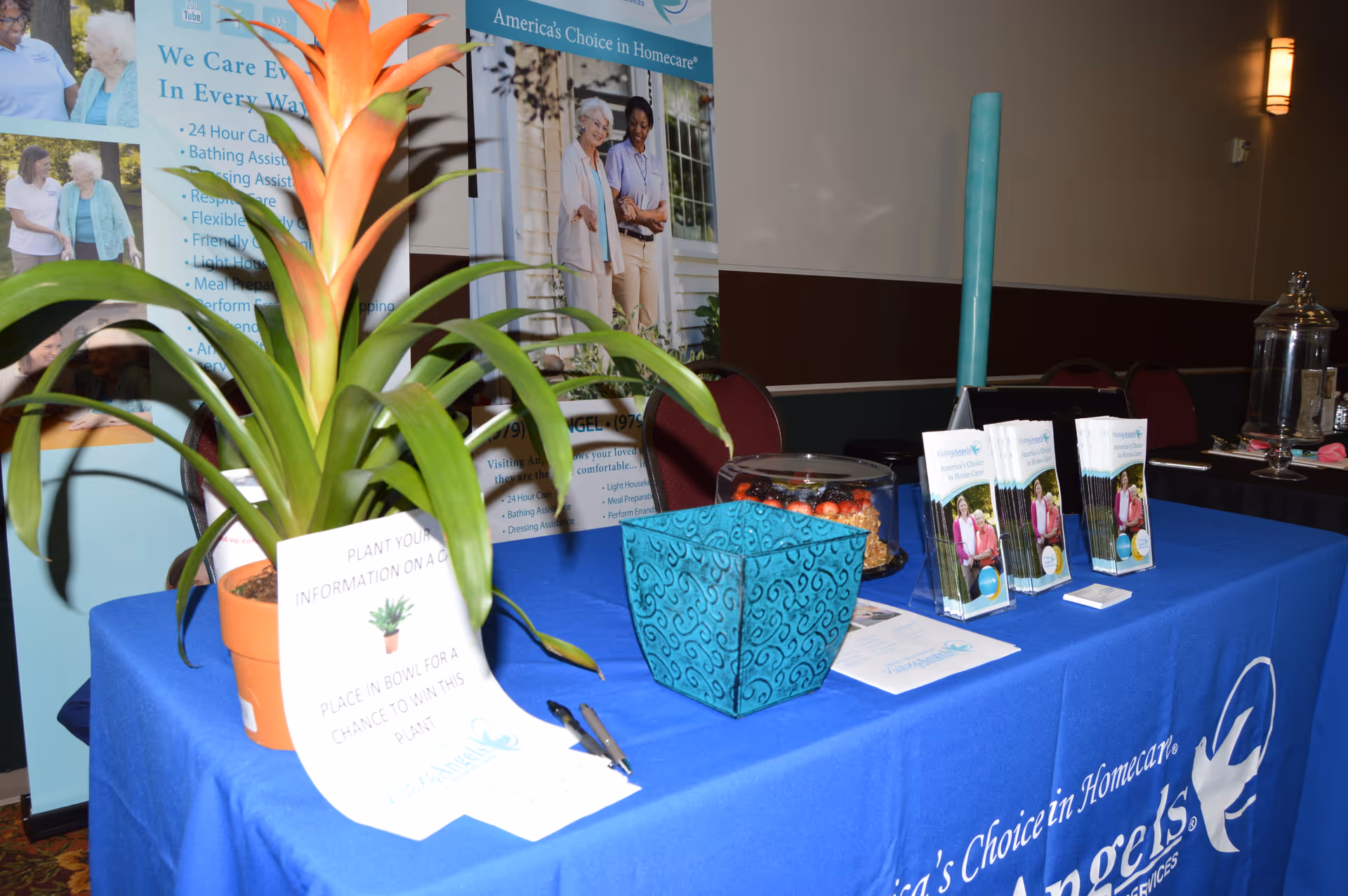 An indoor information booth promoting Visiting Angels senior home care with brochures.