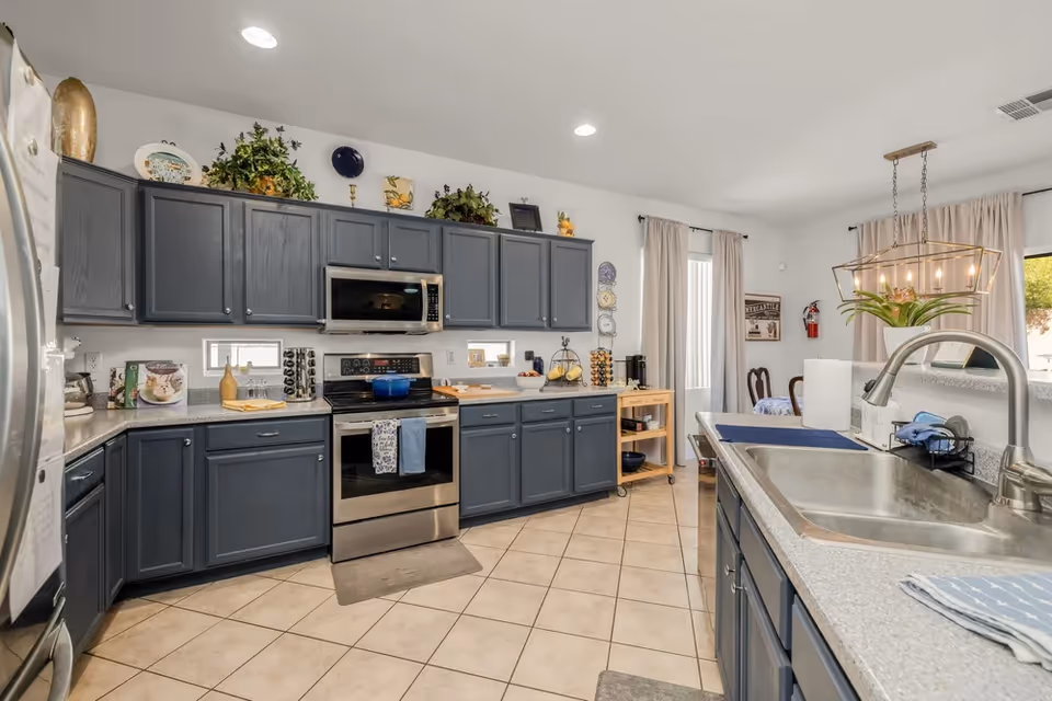Spacious modern kitchen with dark gray cabinets, stainless appliances, and a double sink island.