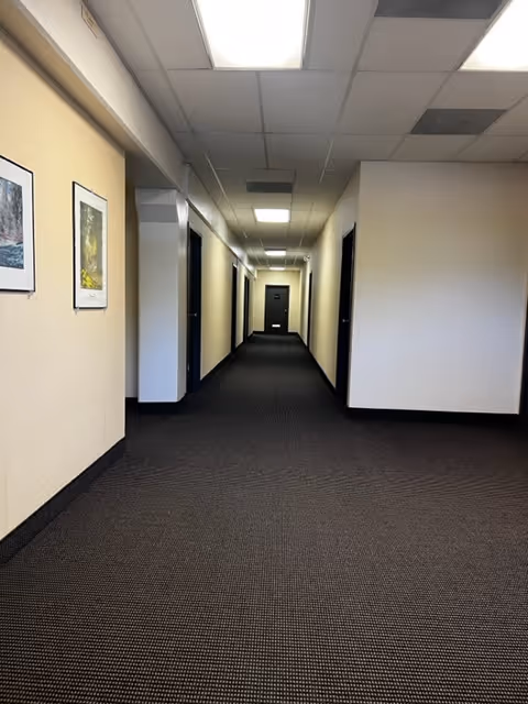 Long, well-lit hallway in a senior care facility with doors along both sides.