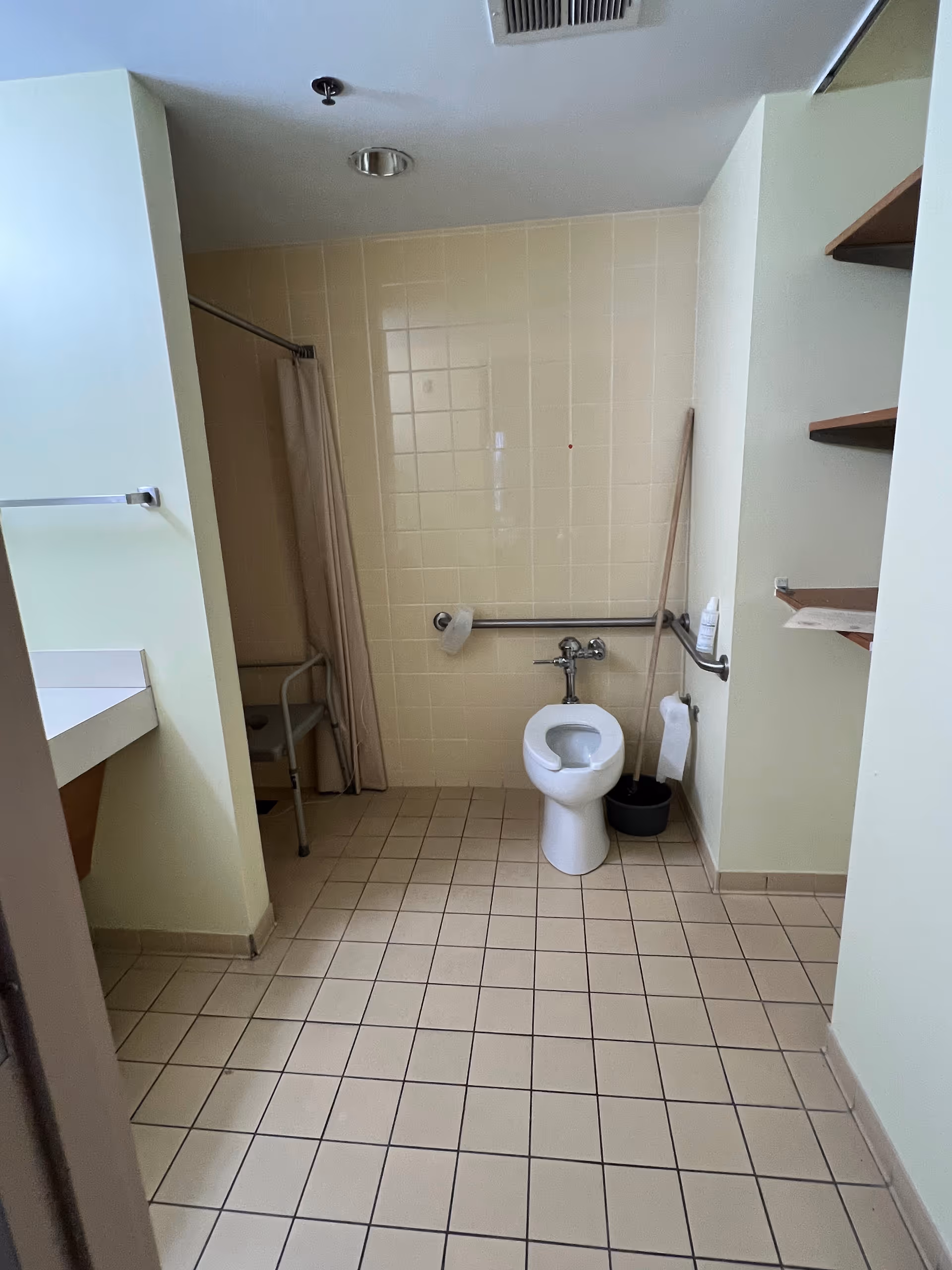 Accessible bathroom in a senior facility with a toilet, grab bars, and shower curtain.