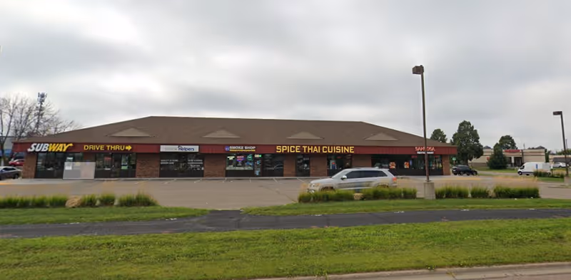 Exterior strip mall with Senior Helpers sign and adjacent Subway and Spice Thai Cuisine storefronts.