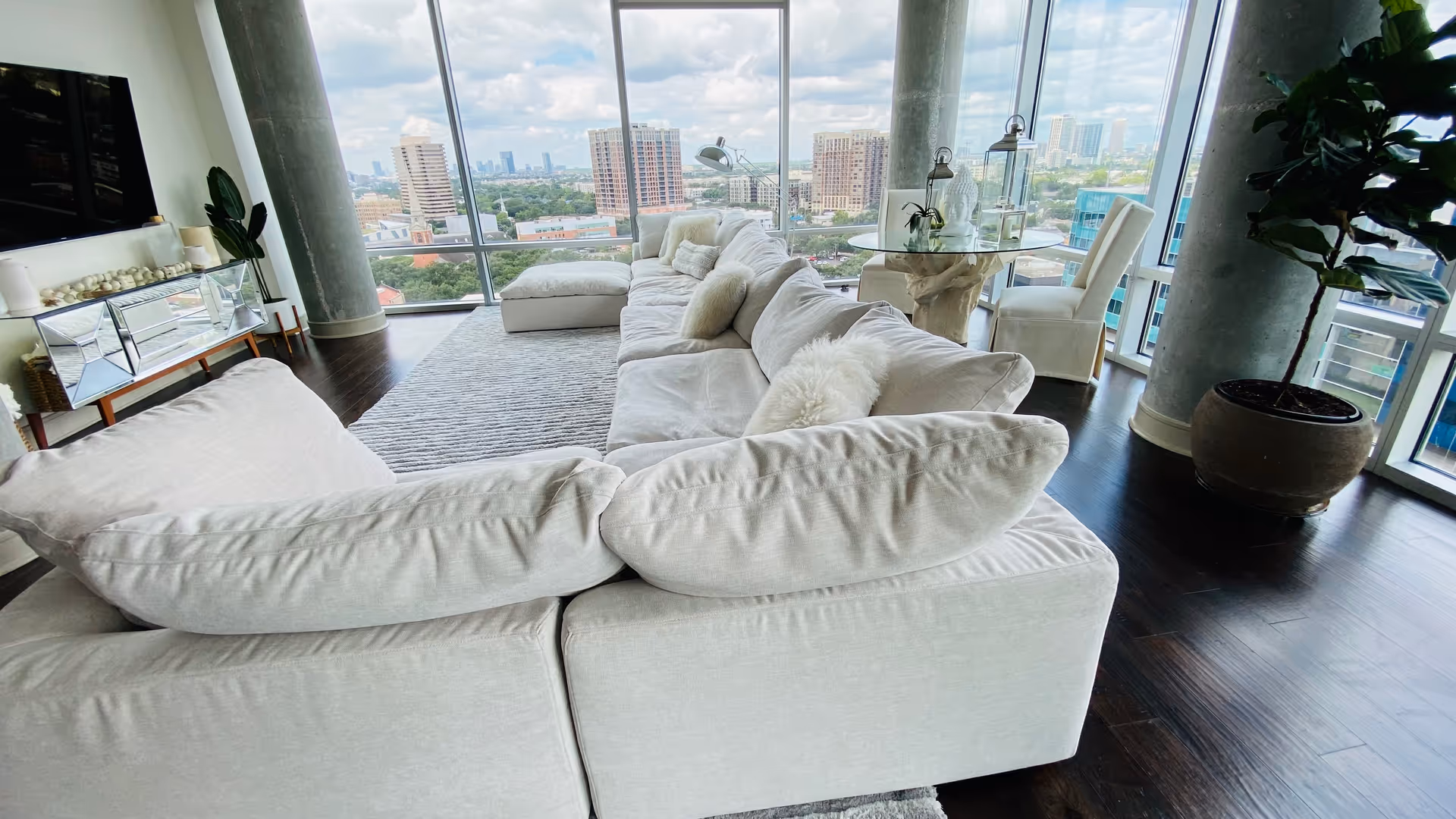 Bright modern living room with a white sectional sofa and expansive city view.