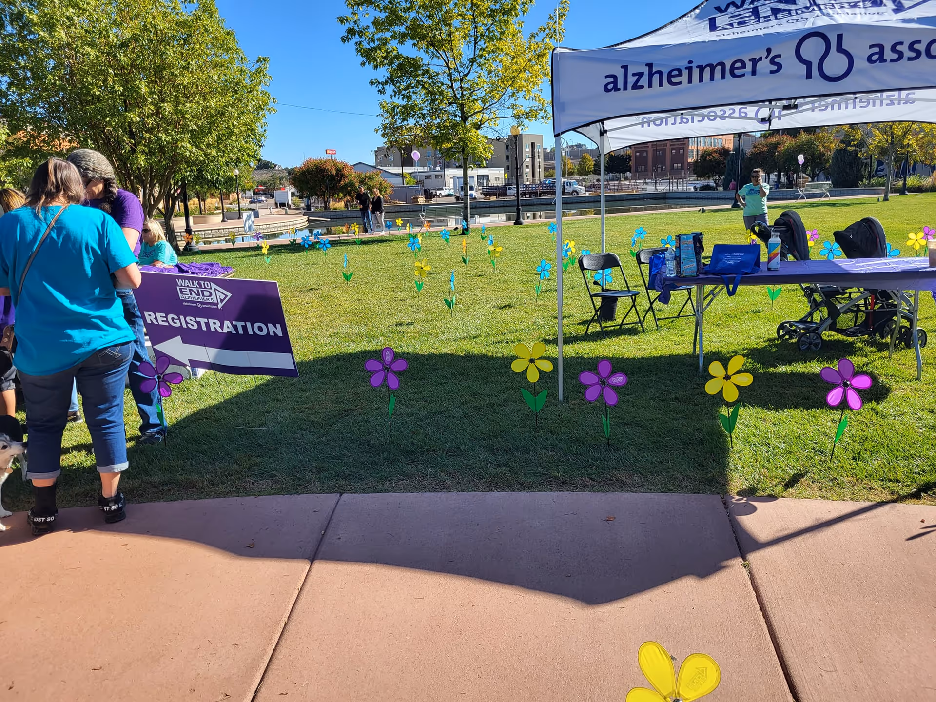 Outdoor park scene with an Alzheimer's Association tent, registration sign, and volunteers.