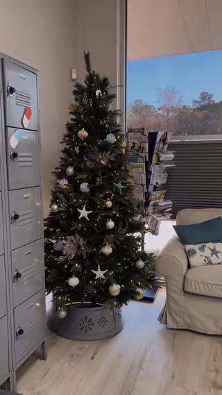 Indoor lounge area with a Christmas tree beside gray lockers and a beige sofa.
