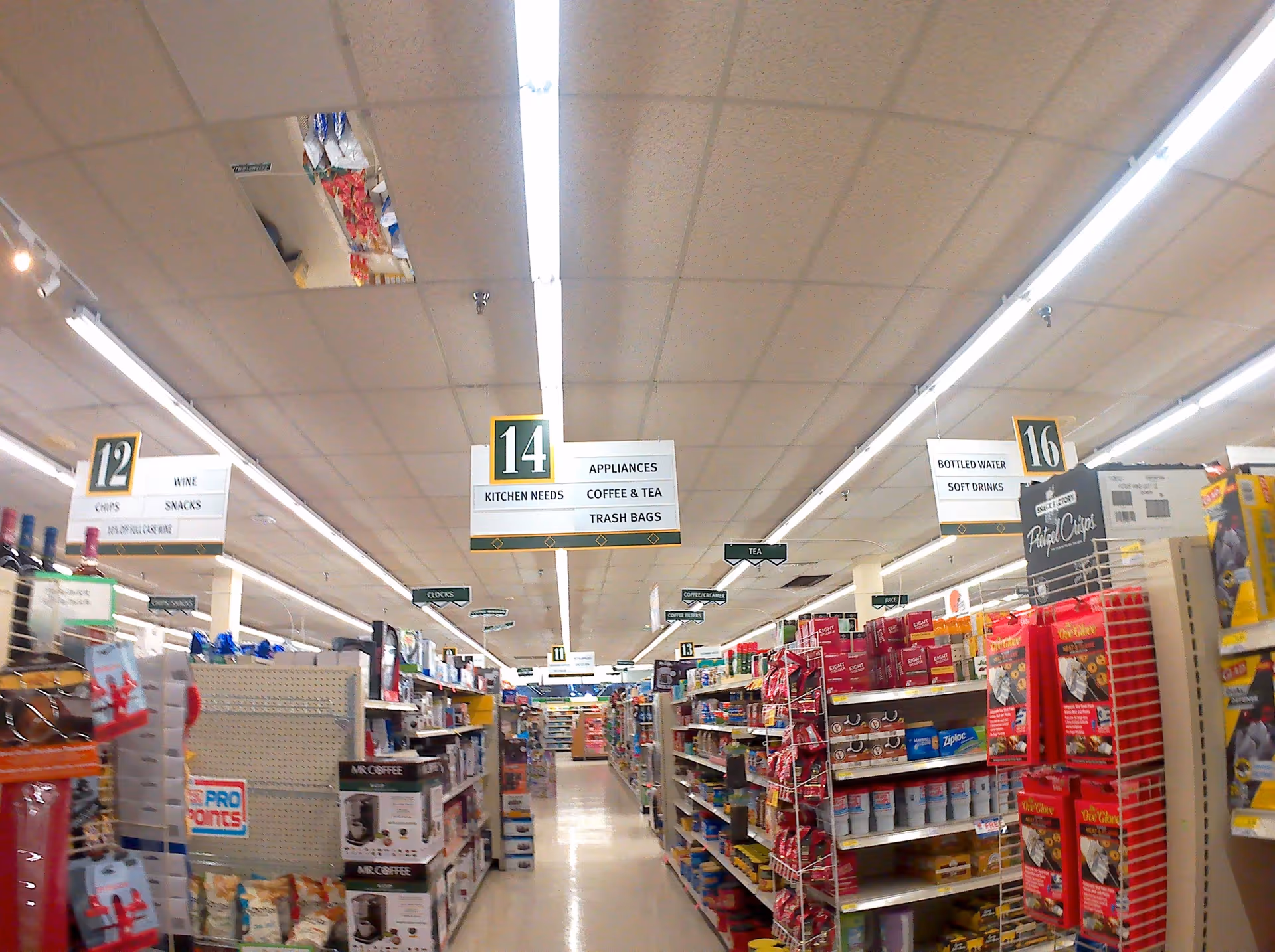Interior of a Discount Drug Mart store featuring a long aisle, overhead signs, and stocked shelves.
