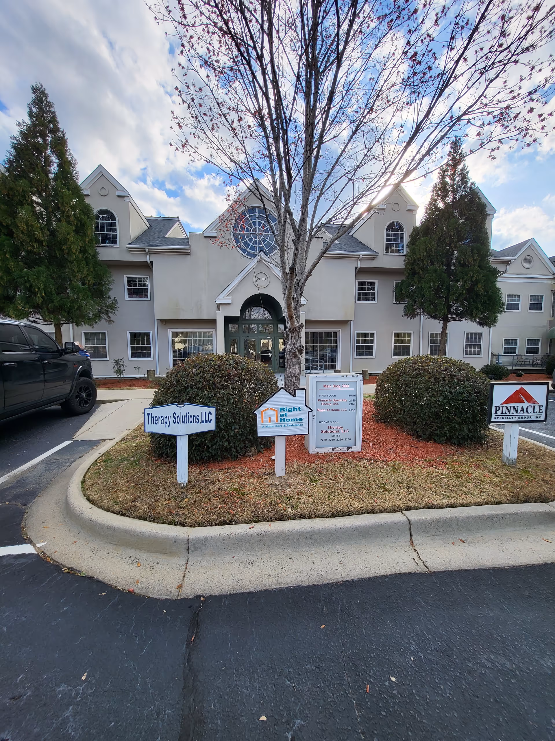Exterior view of a senior living building with signage and landscaped front yard.