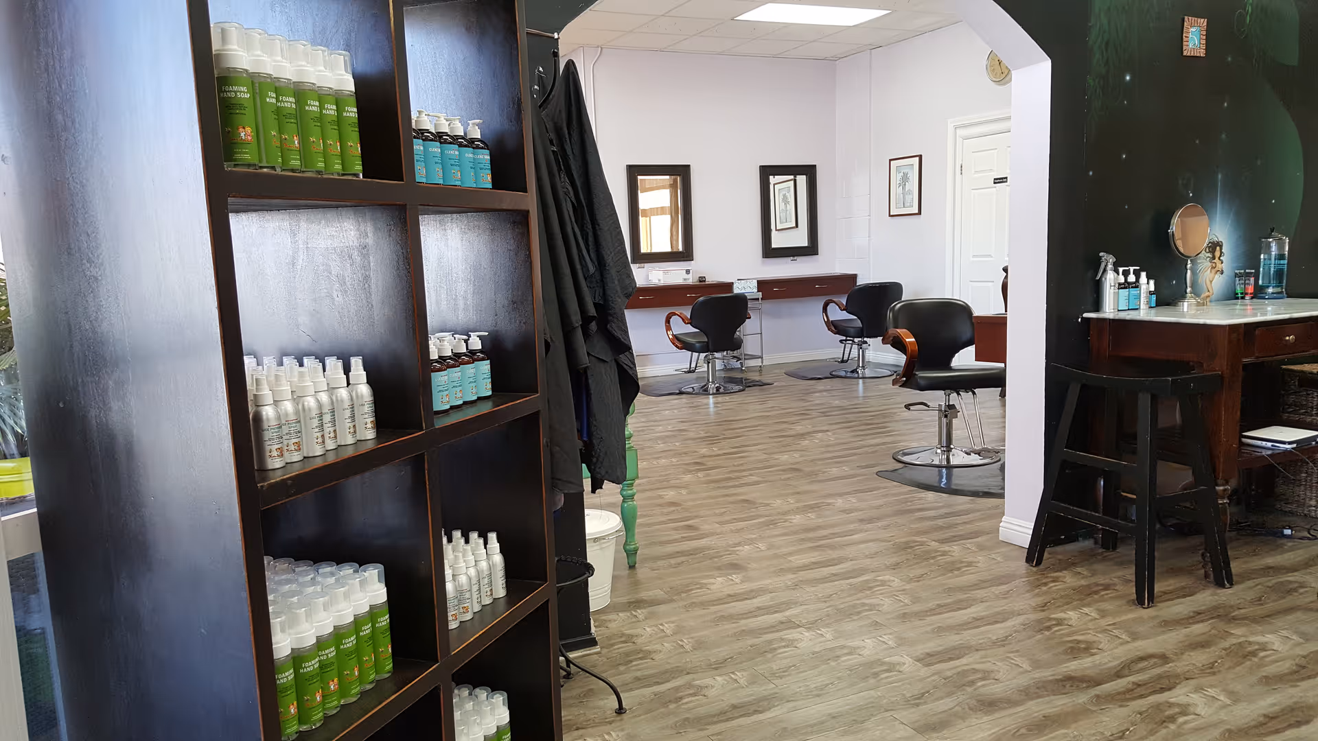 Interior view of a hair salon area with shelves, chairs, and mirrors