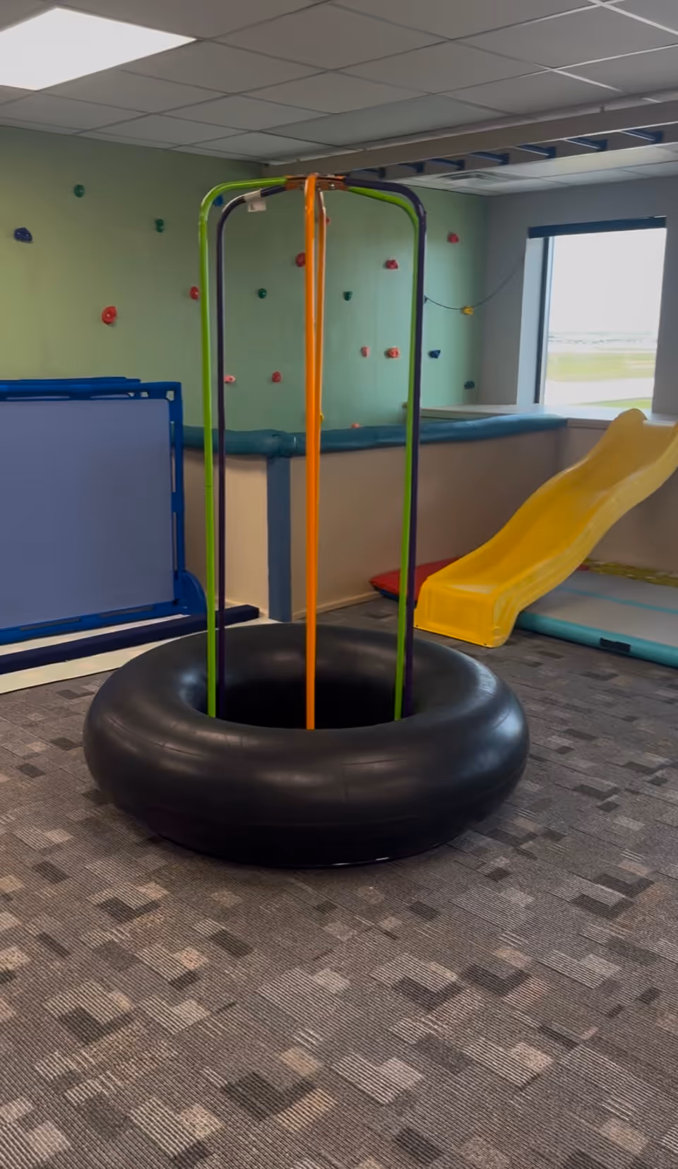 Indoor play area in a senior facility with inflatable ring, slide, and climbing wall.
