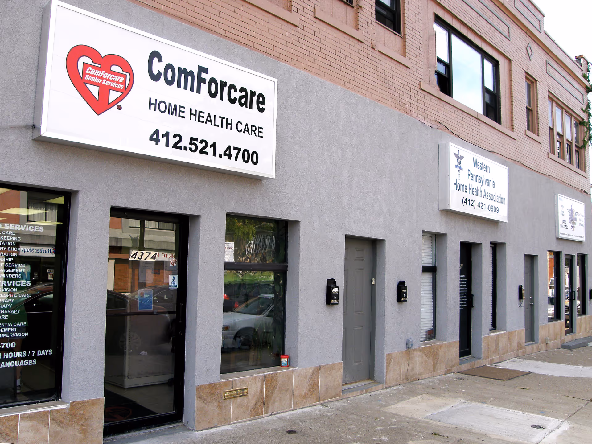 Exterior view of a ComForCare building with multiple business signs along the sidewalk.
