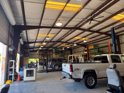 Interior vehicle service bay with lifted vans, tools, and tall shelving.