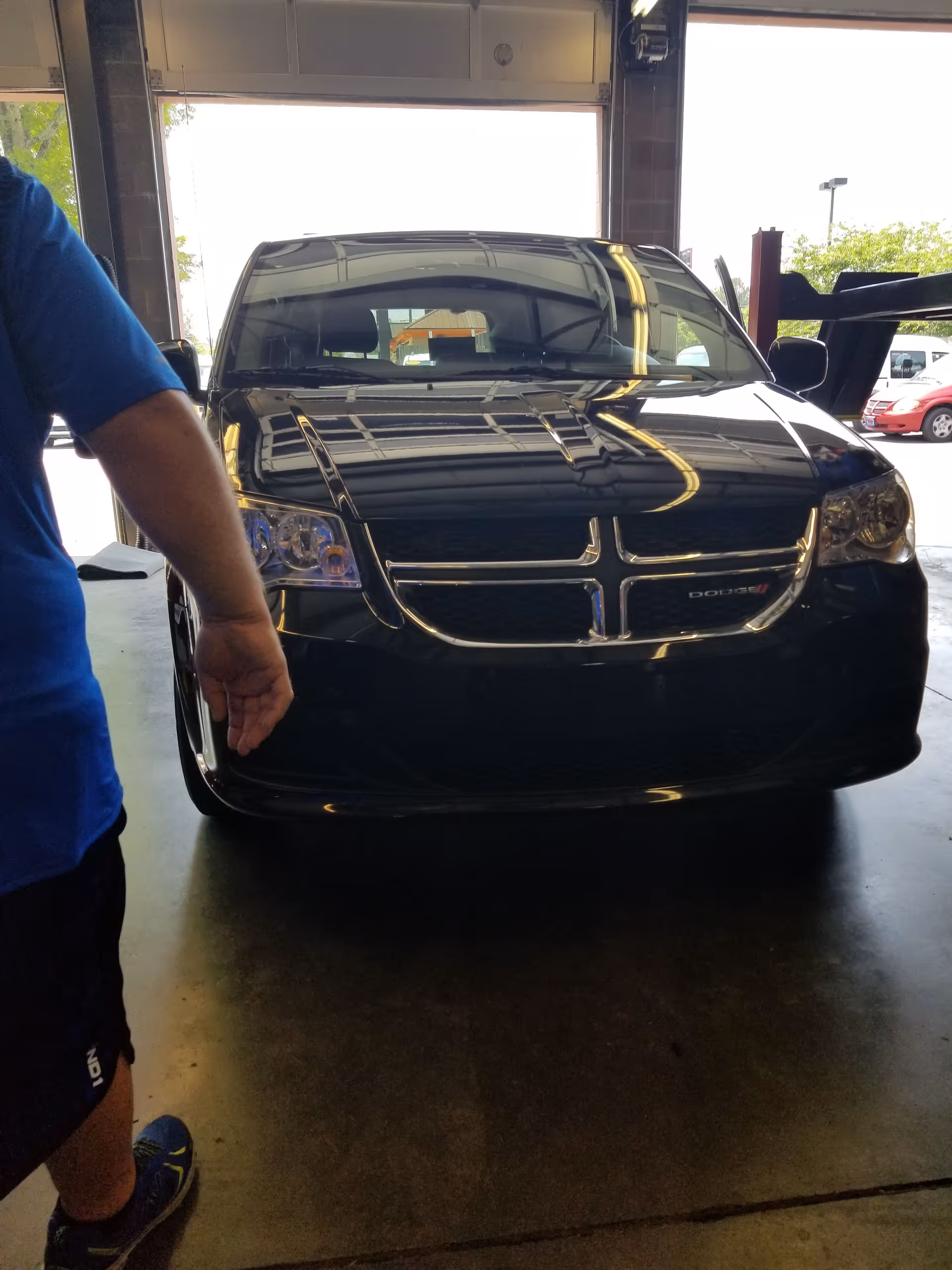 Front view of a black SUV inside a service bay with a blue-shirted person at left