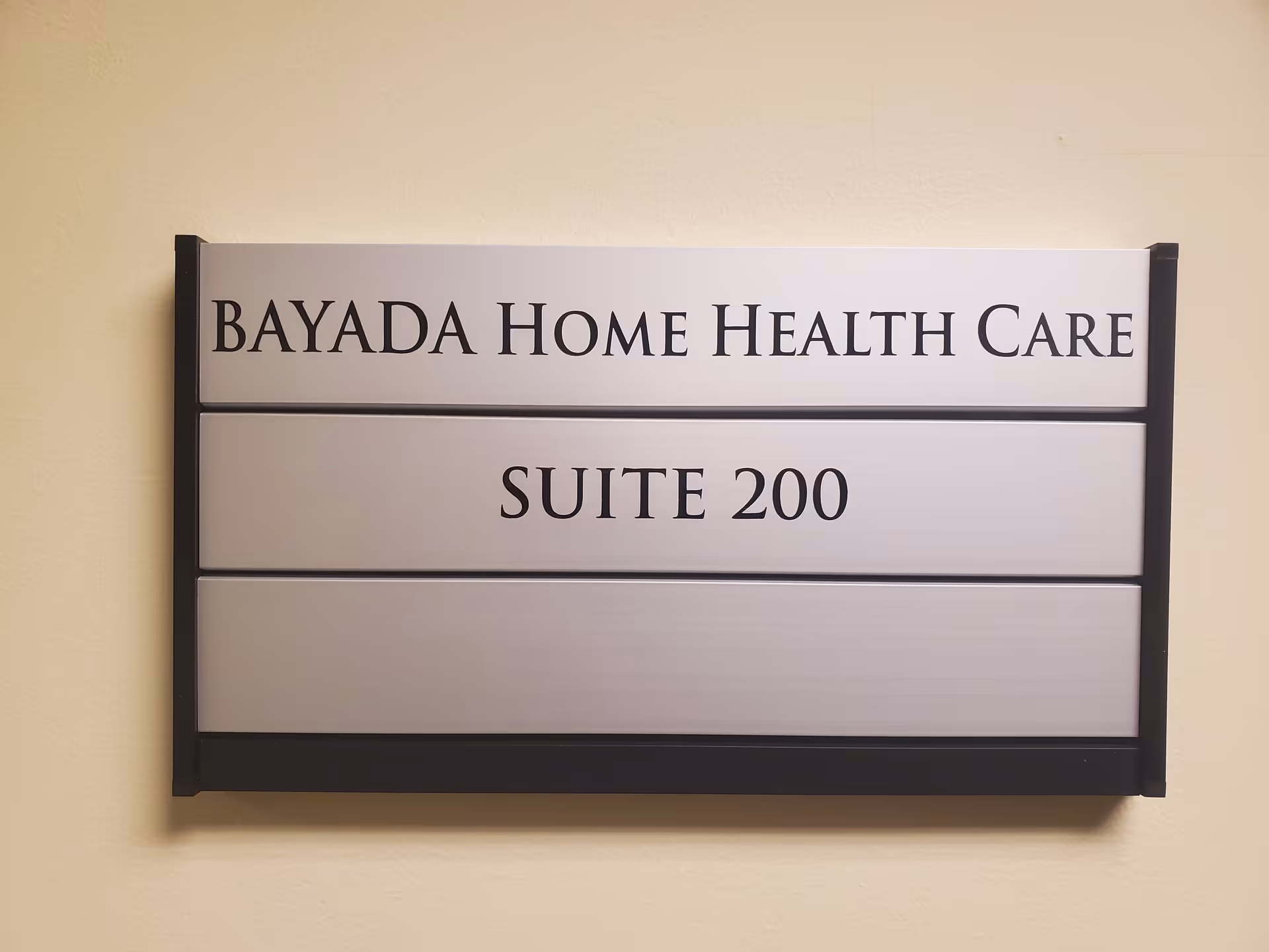 Indoor wall sign reading BAYADA HOME HEALTH CARE, SUITE 200, mounted in hallway.