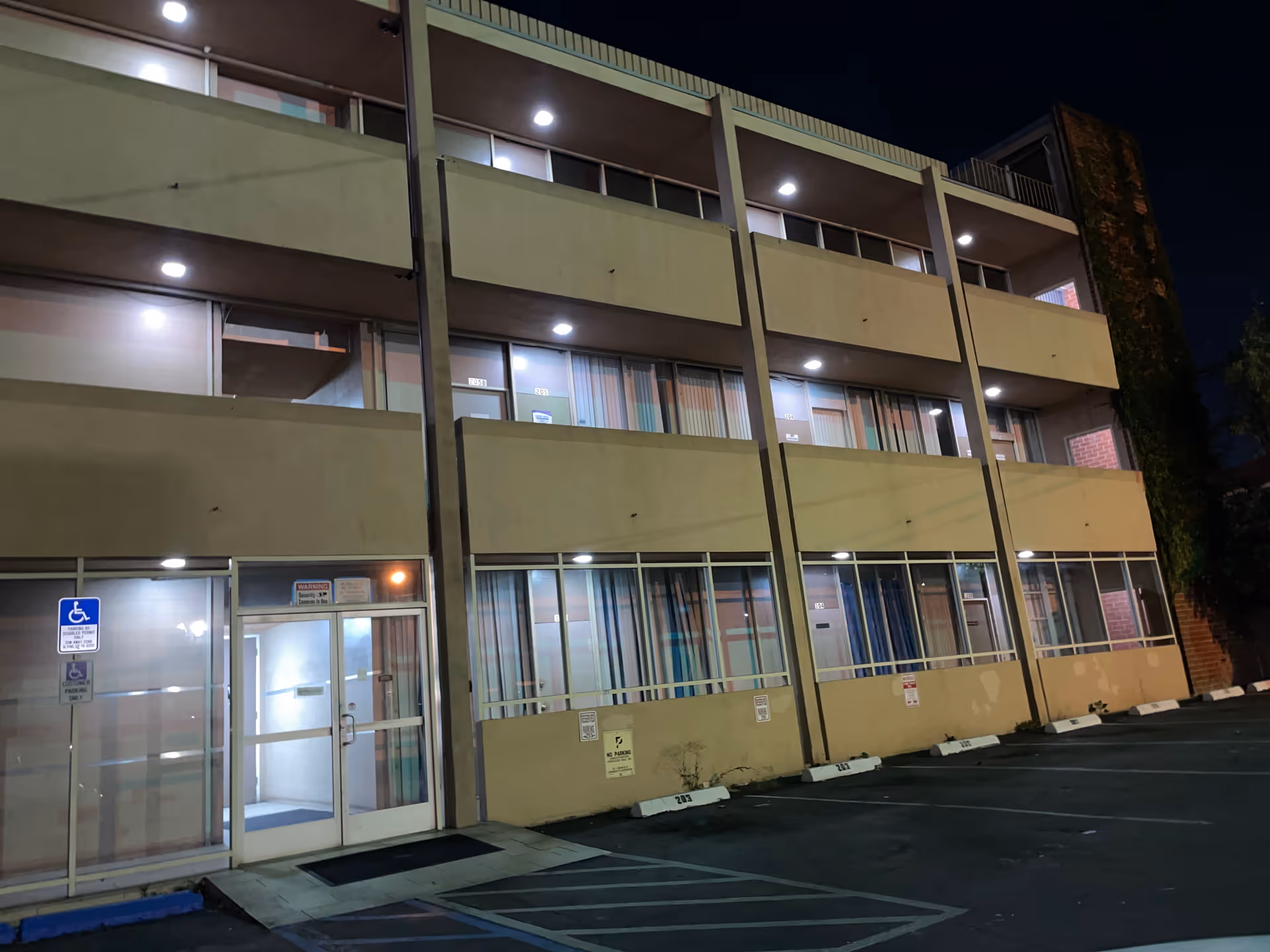 Nighttime exterior of a multi-story senior living building with entrance and parking