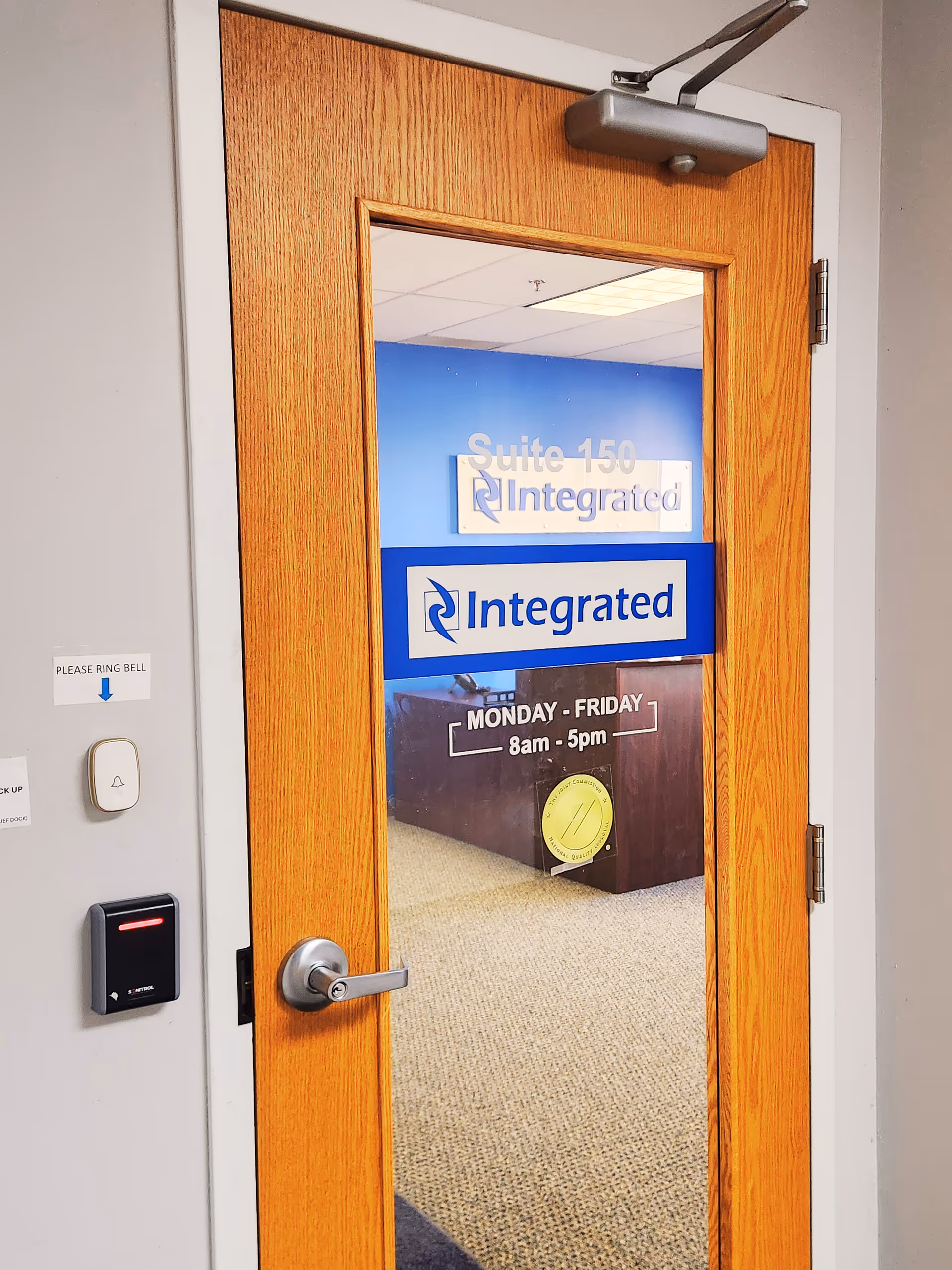 A wooden door with glass panel and blue Integrated signage in a hallway.
