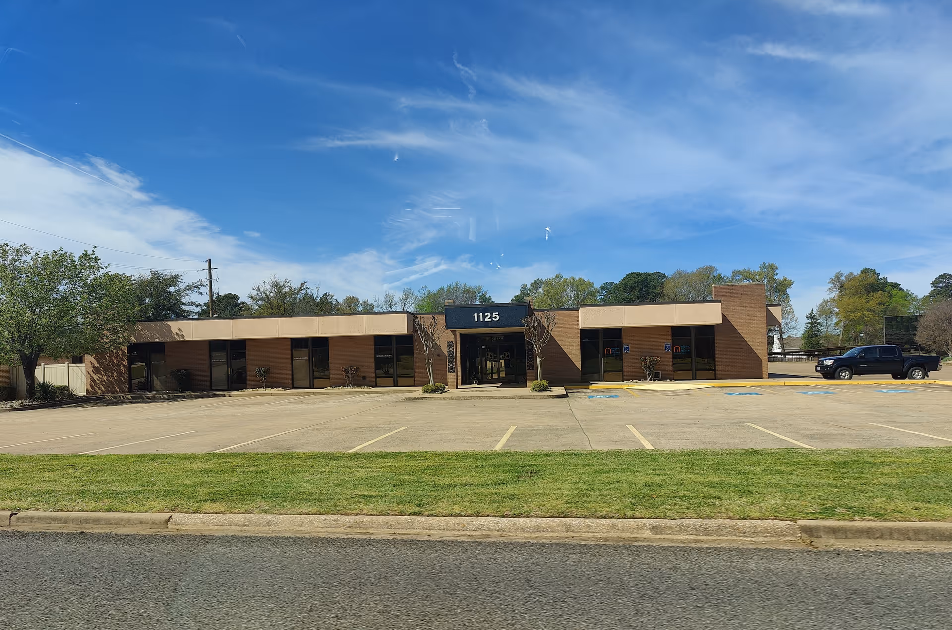 Exterior view of a brick senior living facility with a parking lot.