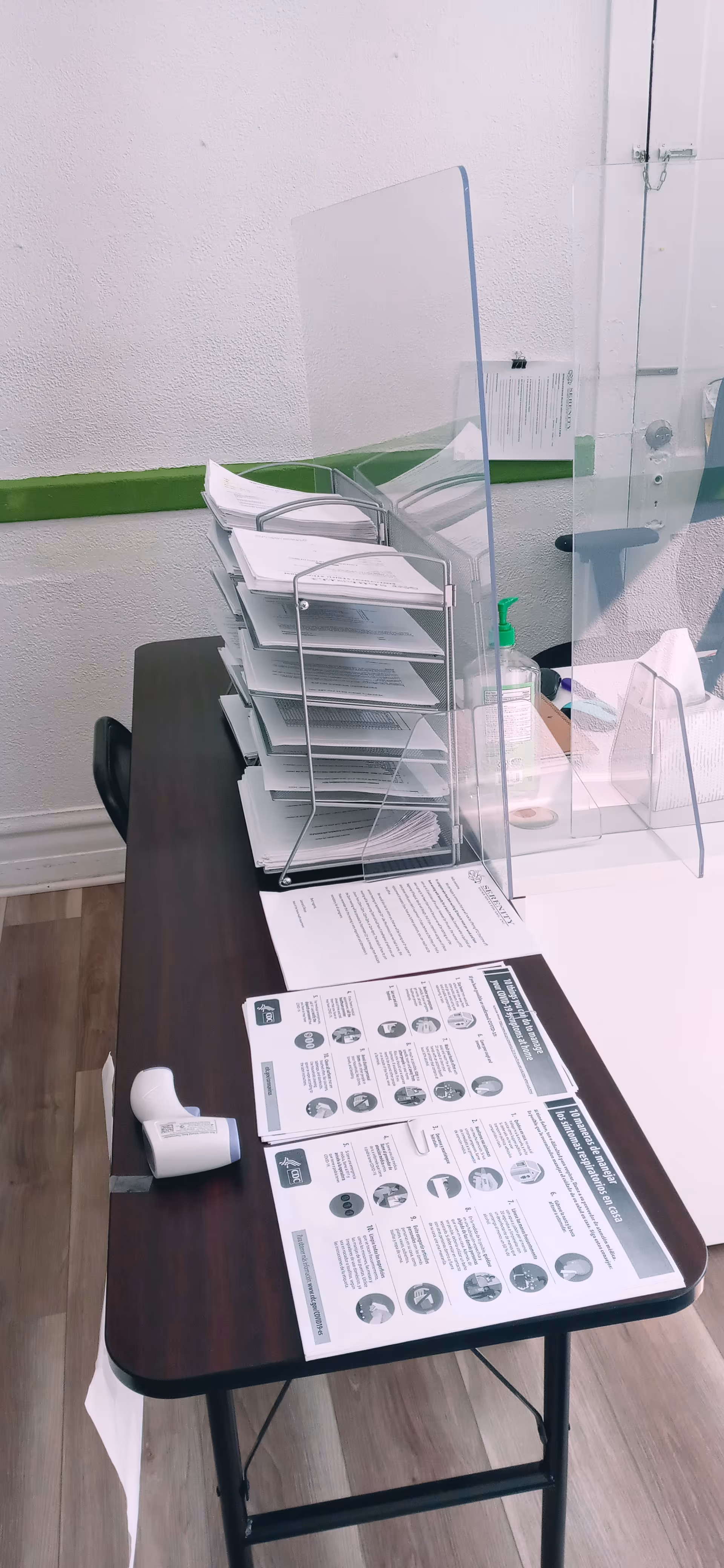 Reception desk with paperwork, a divider screen, and file rack inside Serenity Home Healthcare.