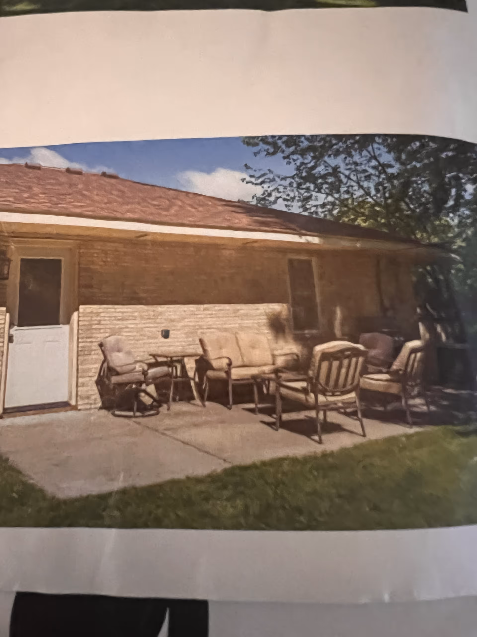 Backyard patio area with outdoor chairs and a sofa set against a brick house.