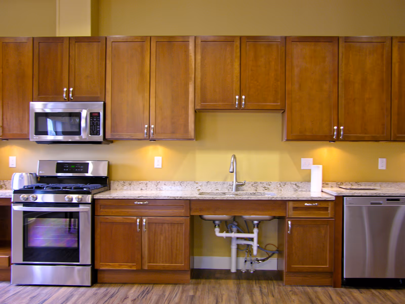 Modern kitchen with wooden cabinets, granite countertops, and stainless steel appliances.