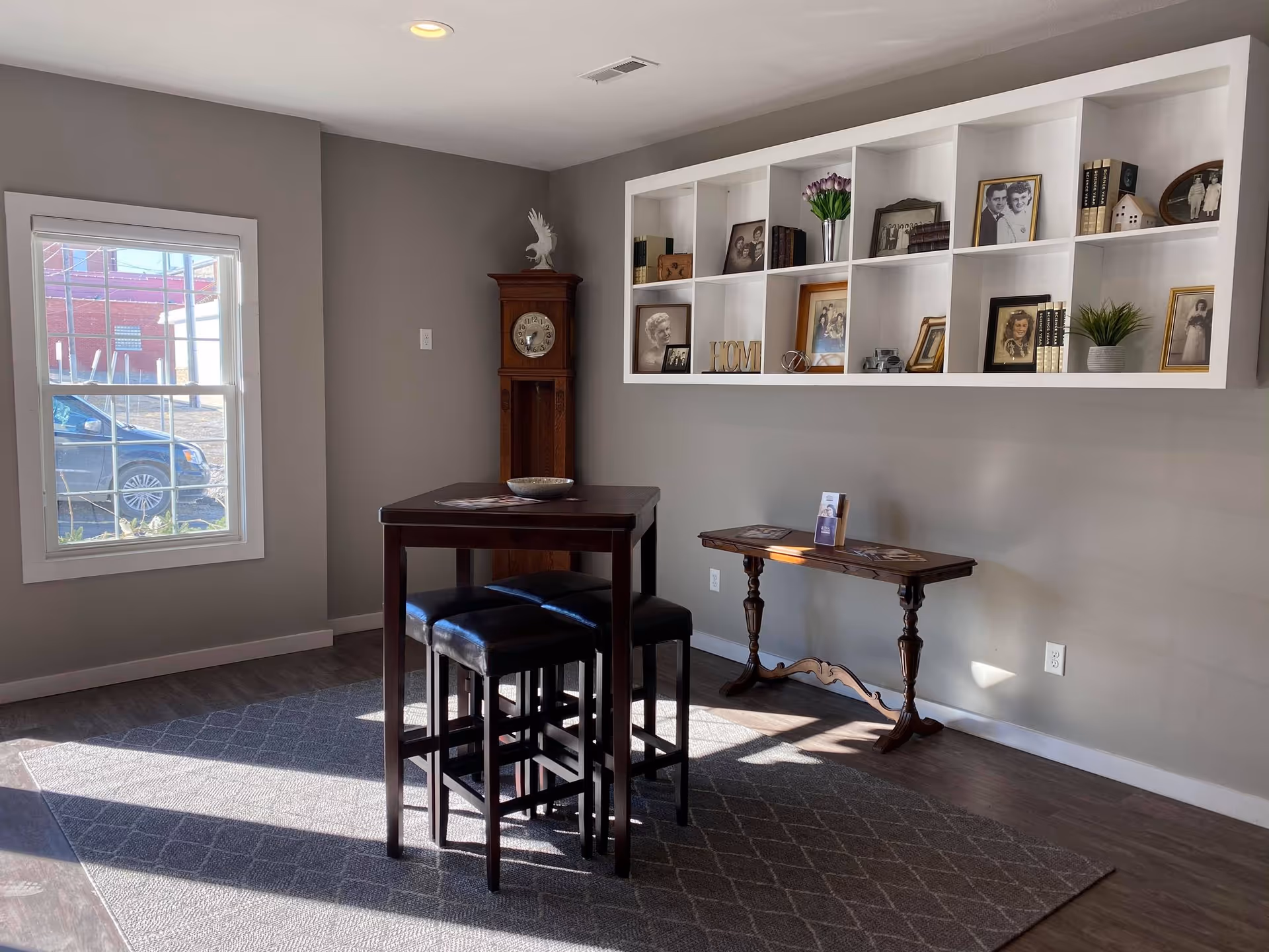 A cozy senior living common area with a high table, stools, and a wall of photos.