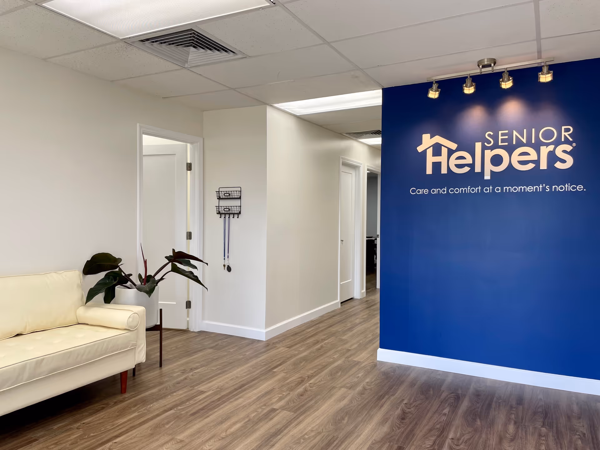 Interior reception area with blue Senior Helpers wall, seating, and hallway.