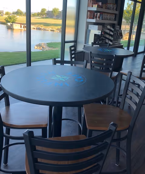 Interior dining area at Traditions Health Hospice with round tables and large windows overlooking a pond.