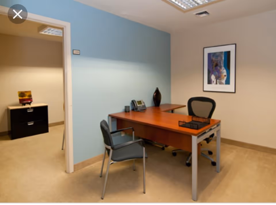 Office desk and chairs in a clean administrative room with blue accent wall.