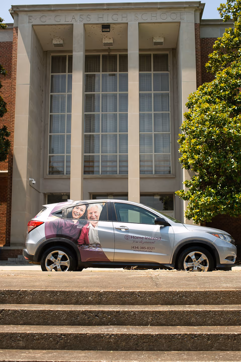 Exterior view of a building front with a branded Home Instead car parked outside.