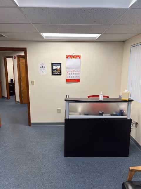 A reception desk in a neutral lobby of a senior living facility with calendar on wall.