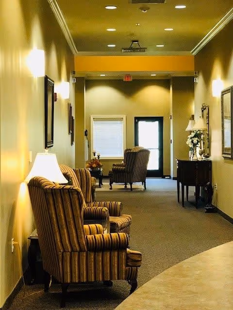 Long, well-lit hallway with striped armchairs, lamps, and a console table.