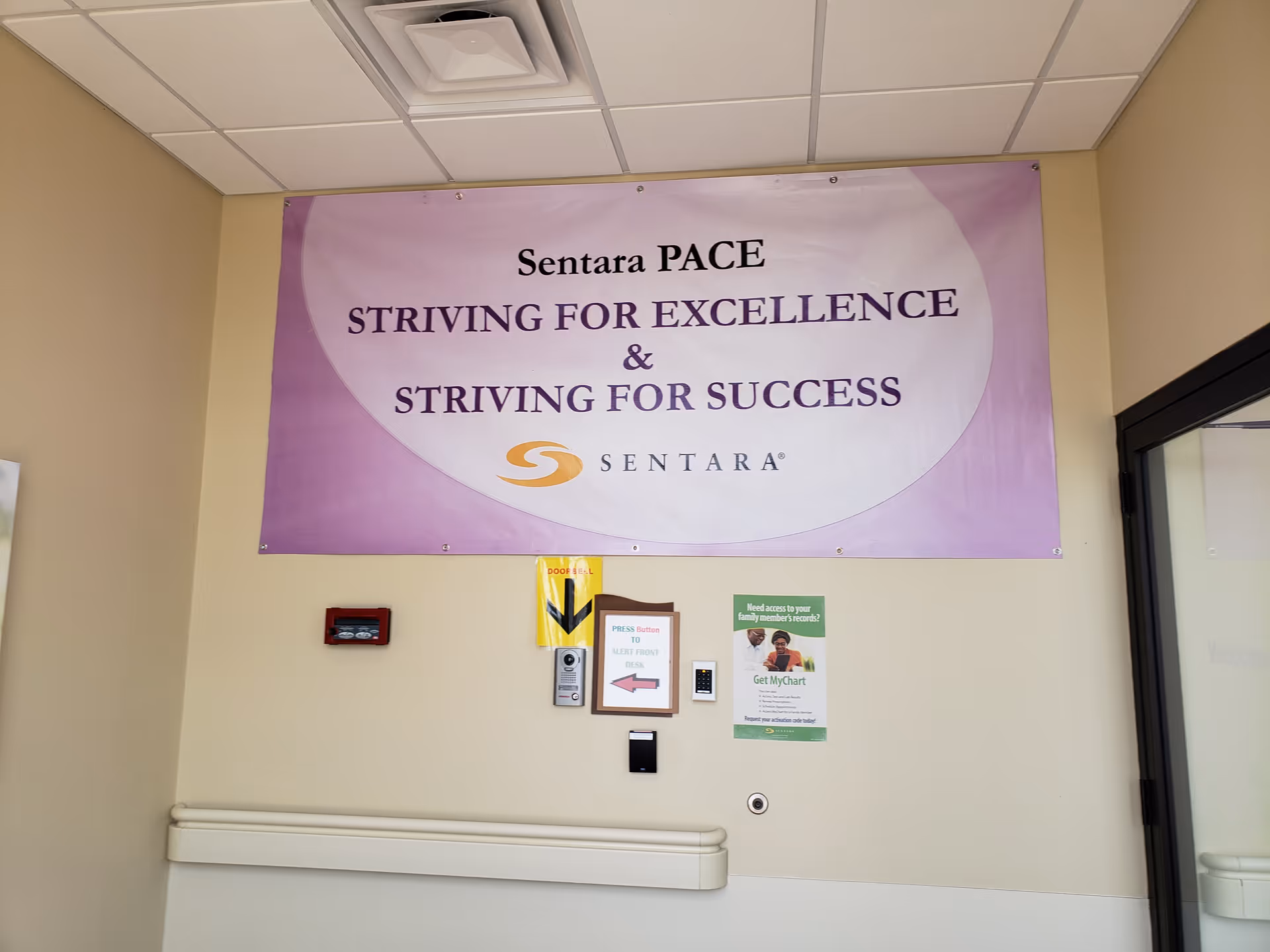 Large purple Sentara PACE banner on a beige hallway wall with safety notices.
