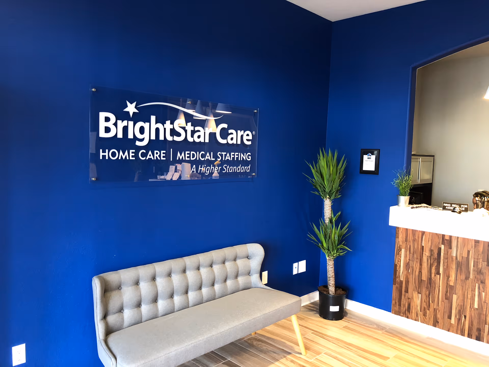 Reception area with blue walls, BrightStar Care sign, bench, and wooden reception desk.