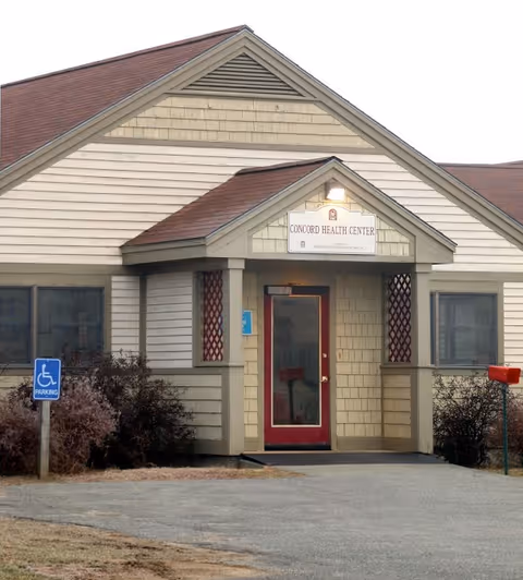 Front view of a beige senior care center building with a red door.