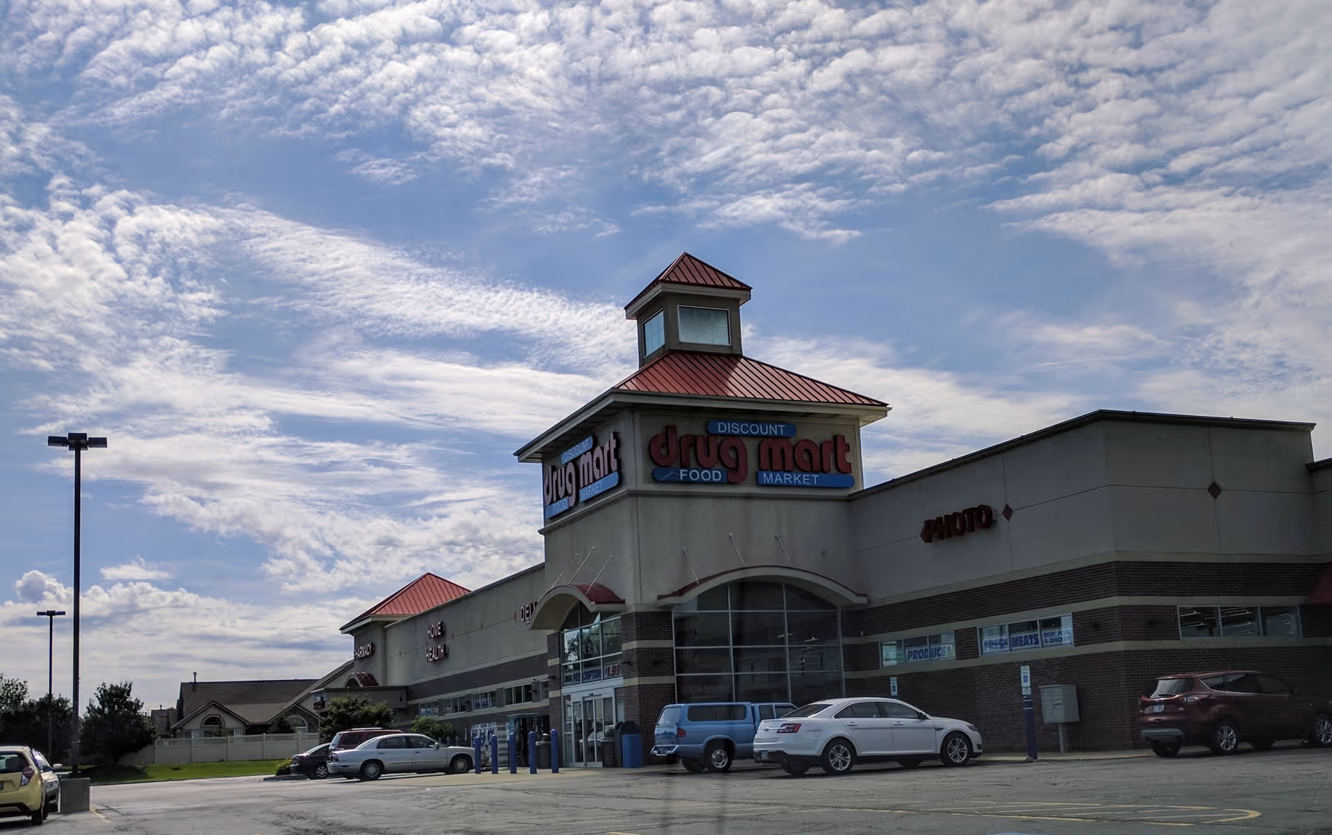 Front view of a Discount Drug Mart building with parking lot and blue sky.