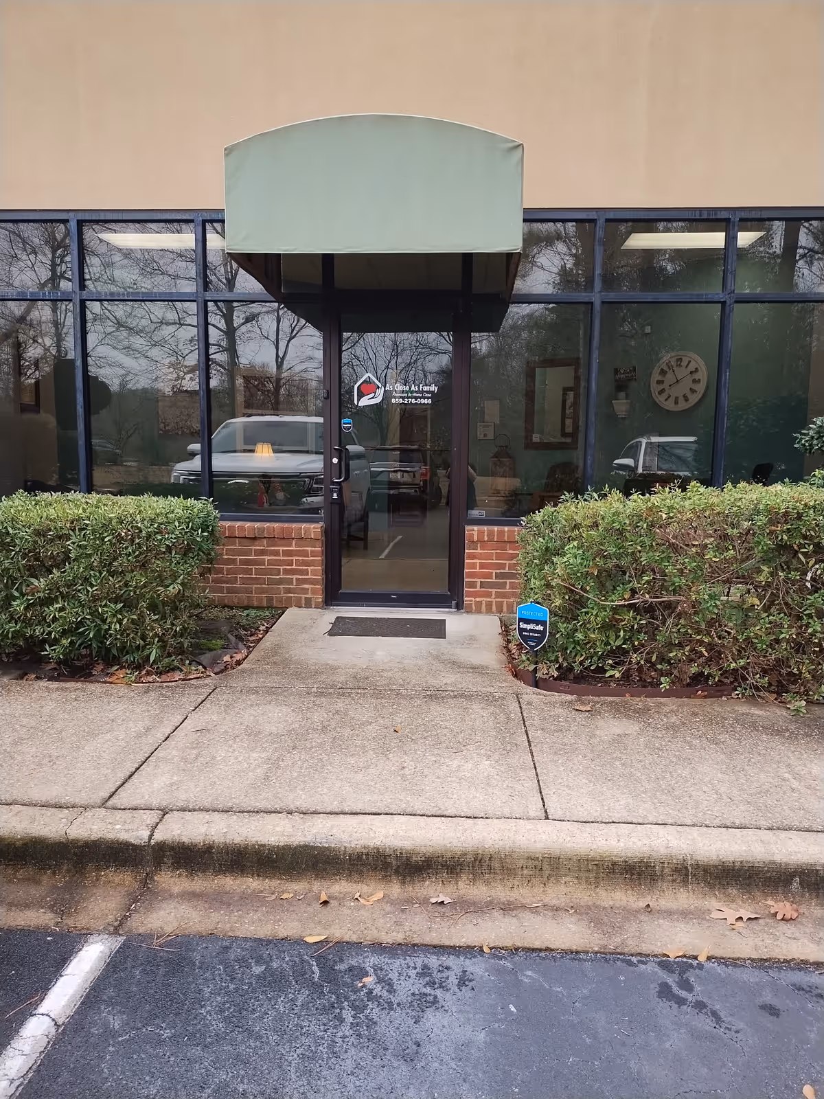 Front entrance of a senior living facility with glass doors and a green awning.