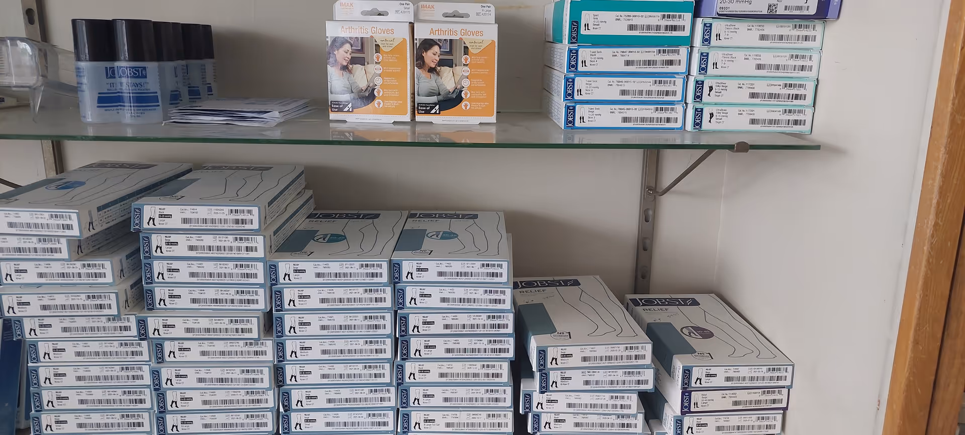 Shelf with arthritis gloves and medical supply boxes in a clinic storage area.