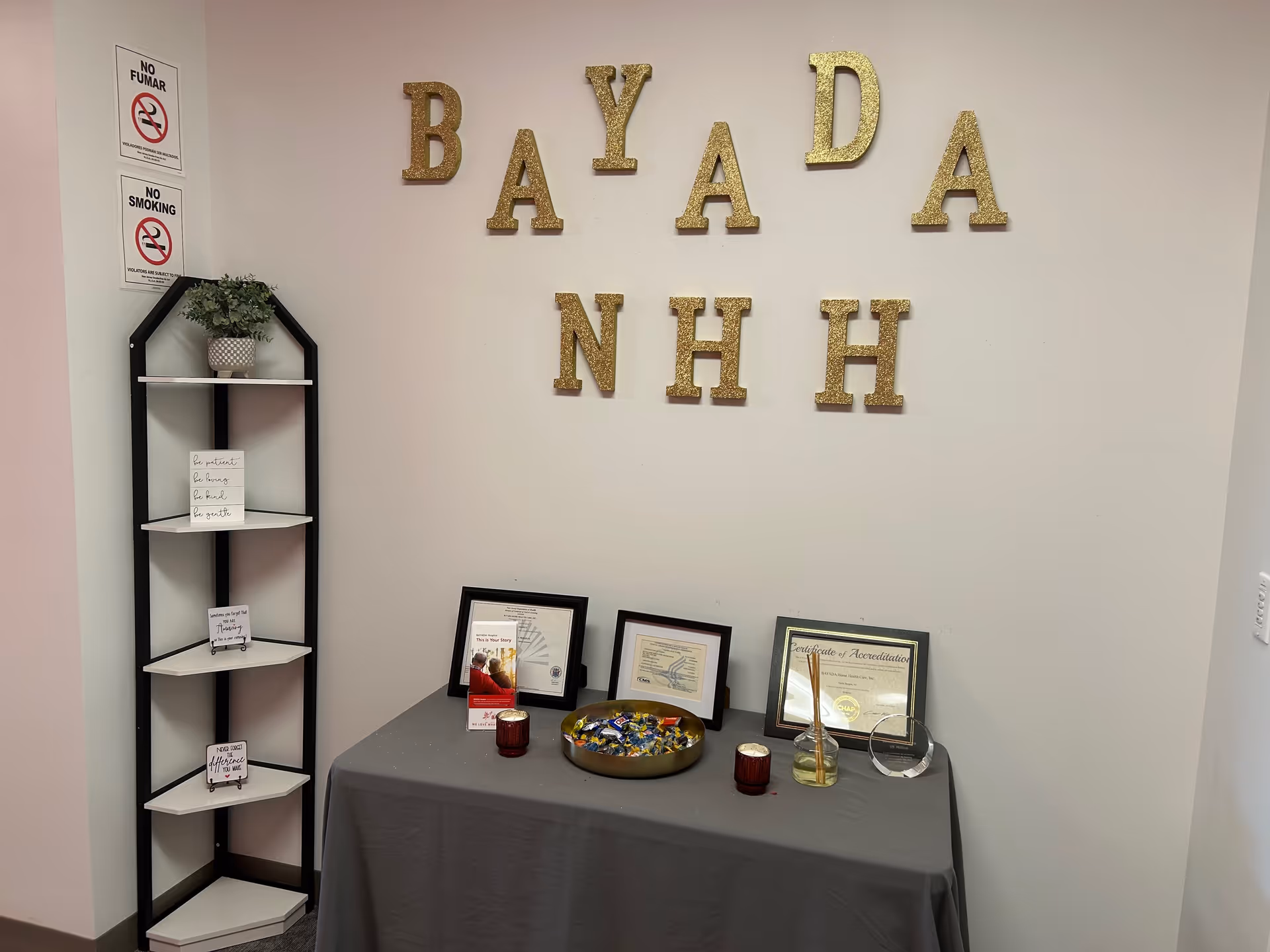 Interior corner featuring BAYADA NH wall letters, table with certificates, and a shelf.