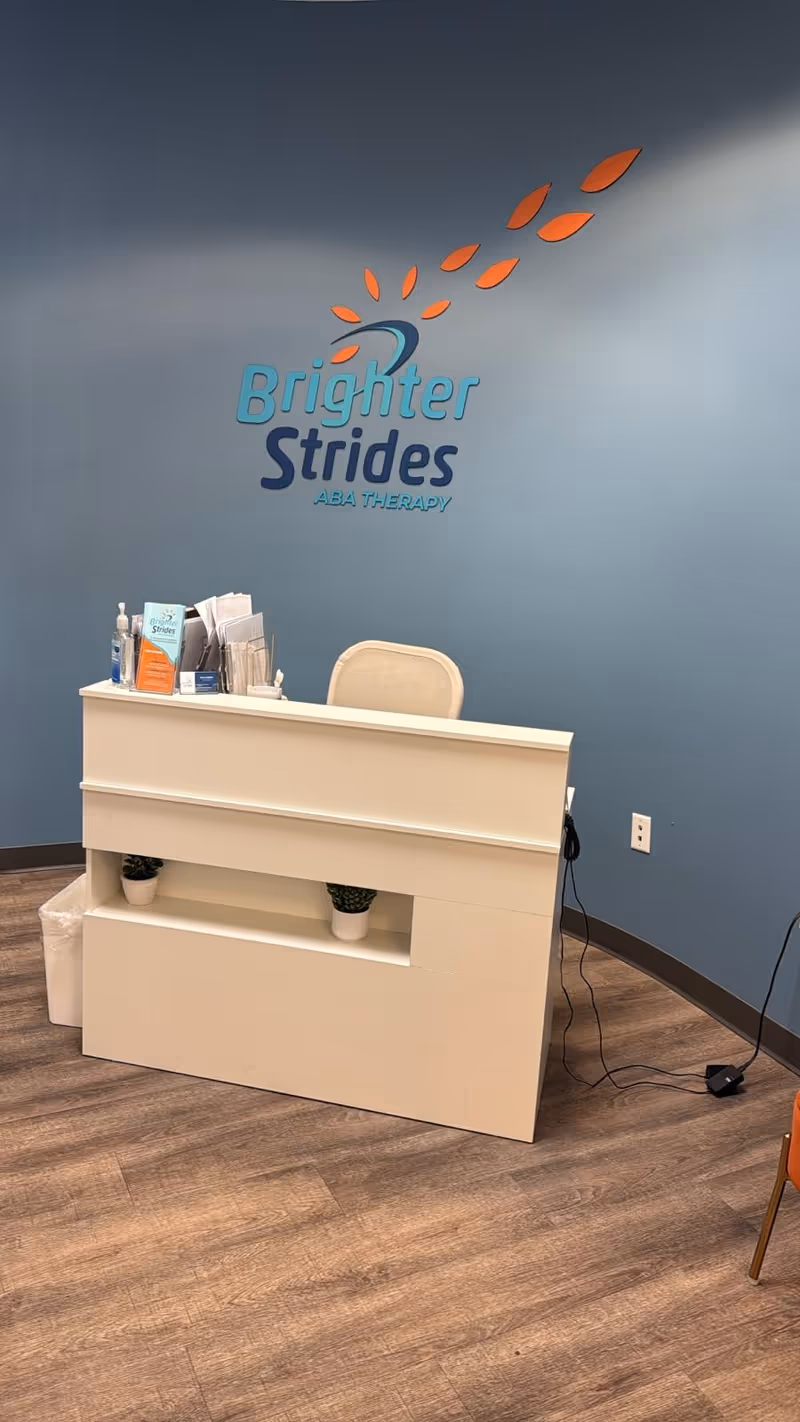 Reception desk against blue wall featuring Brighter Strides ABA Therapy logo.