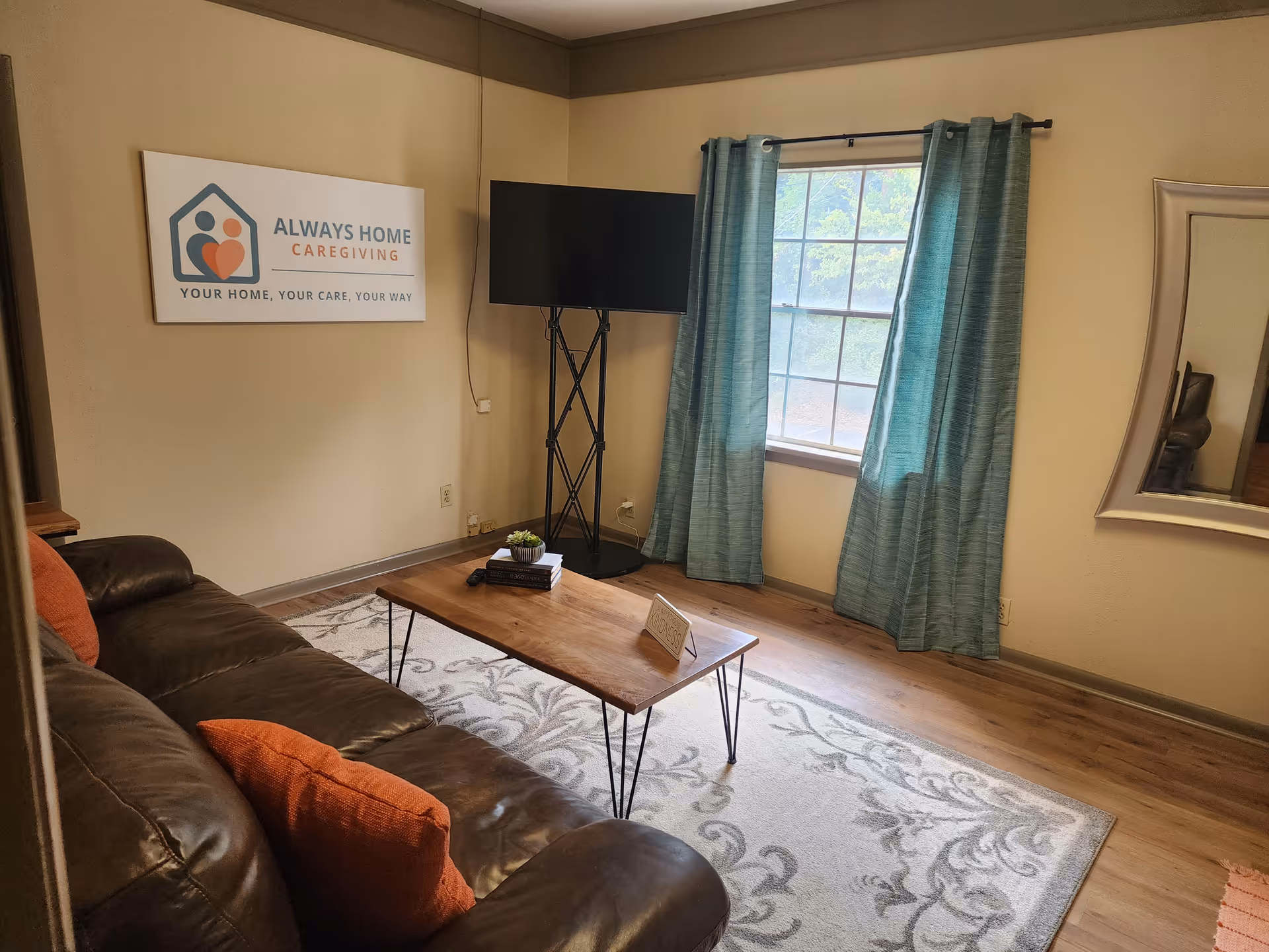 Cozy living room with leather sofa, coffee table, rug, sign, TV, and teal-curtained window.