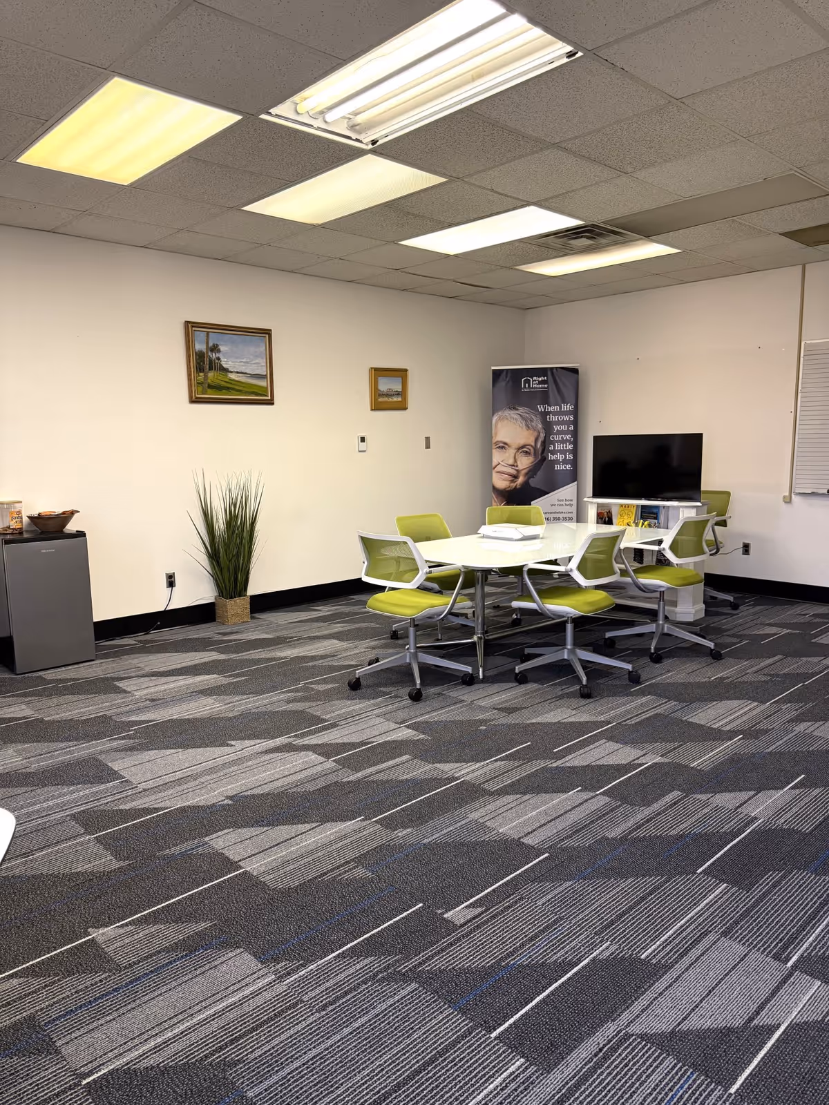 A bright, modern meeting space with lime-green chairs around a white table.