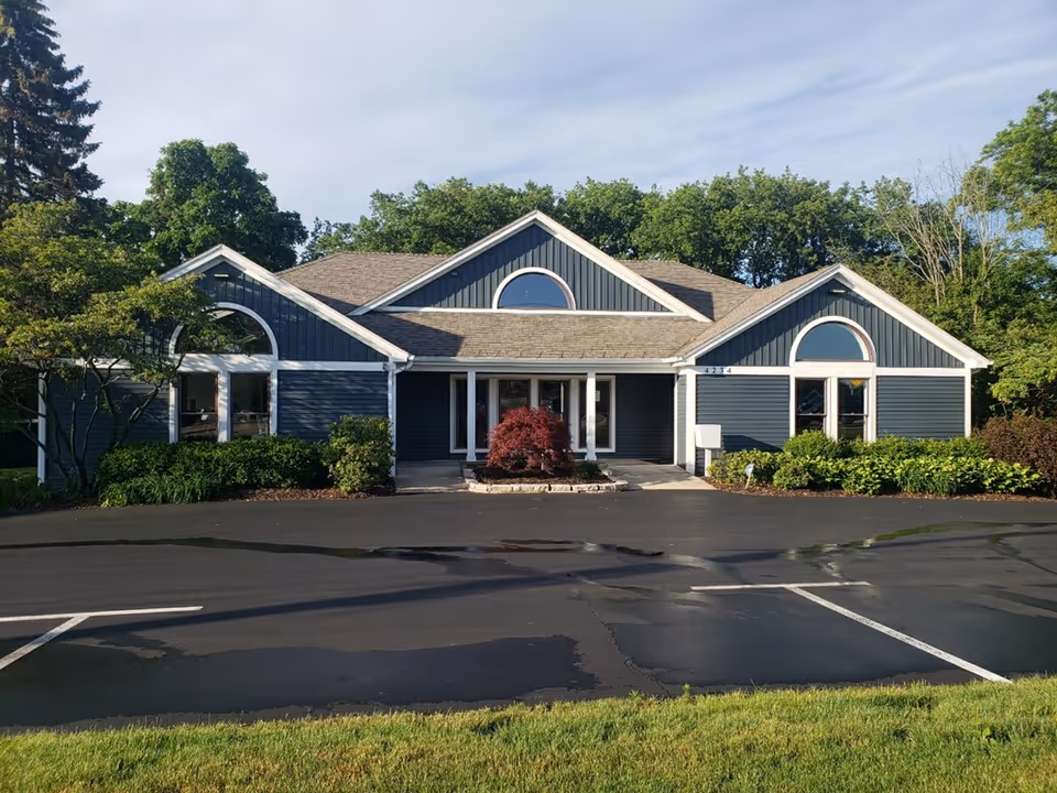 A single-story blue building with arched windows and a parking lot in front.