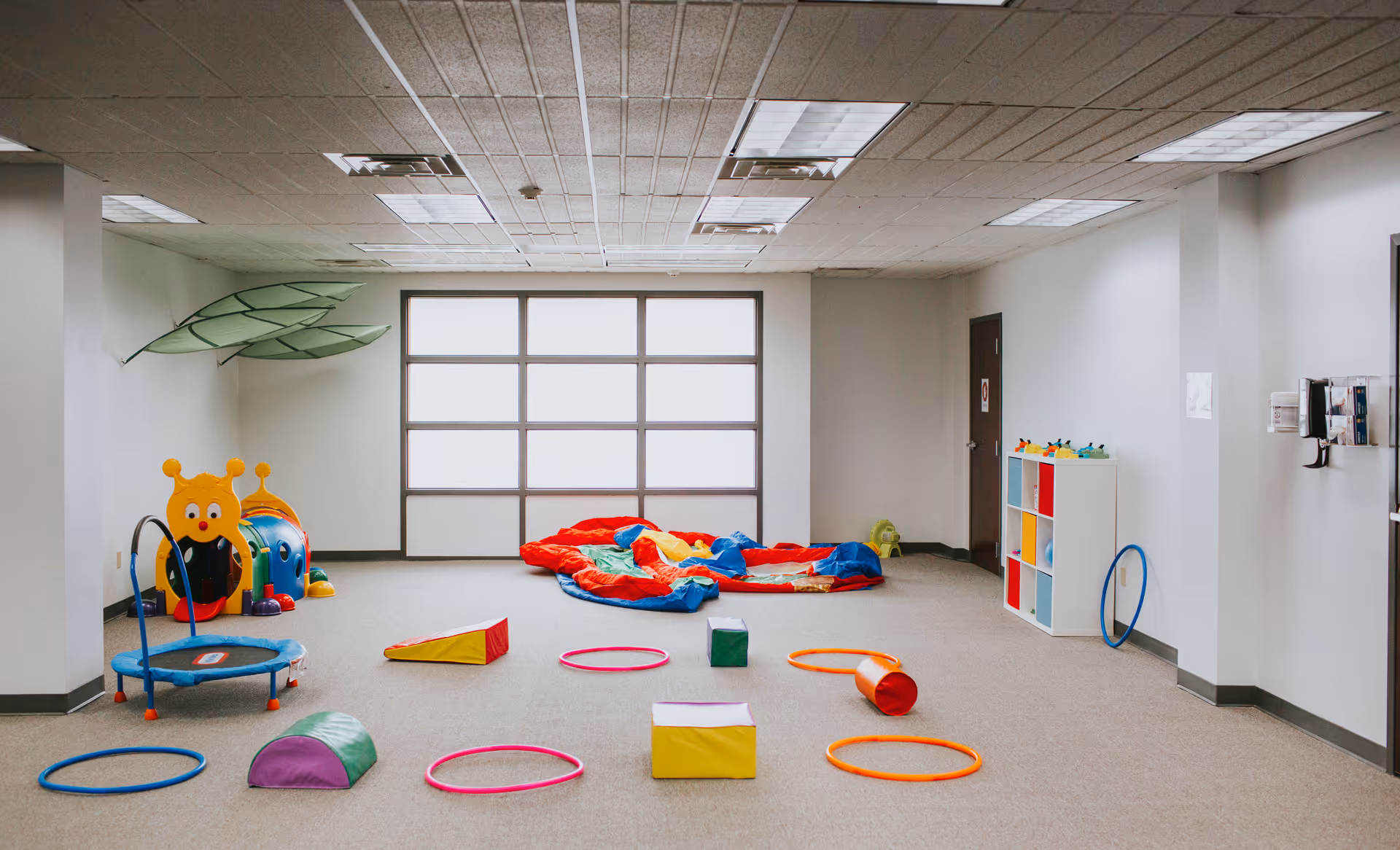 Bright indoor playroom with colorful soft play equipment and storage cubbies.