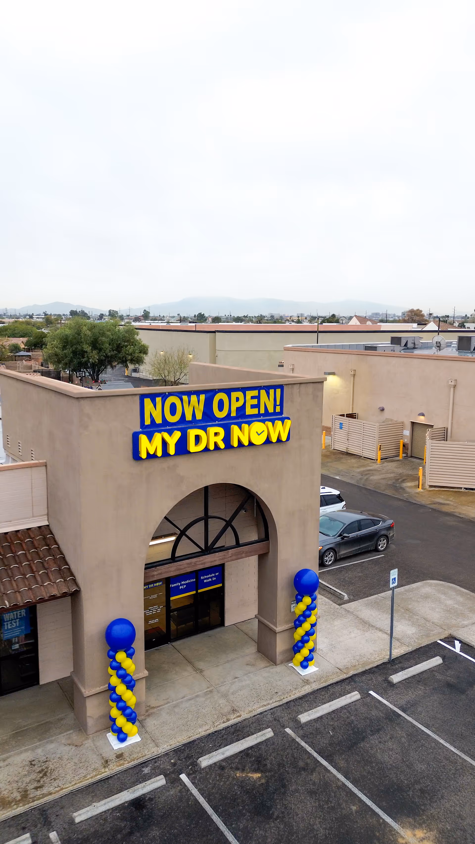 Beige building front with large NOW OPEN! MY DR NOW sign and balloon columns.