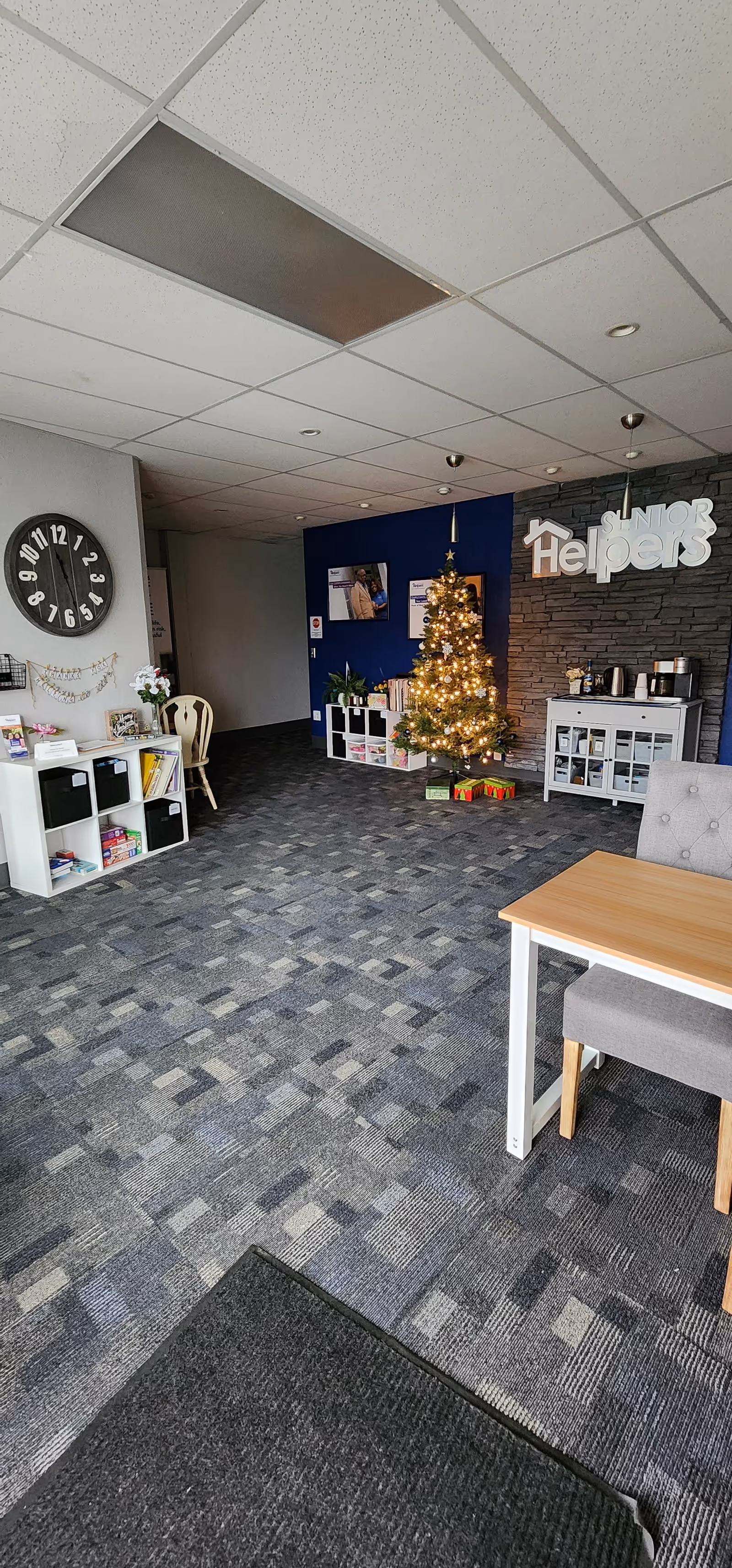 Indoor lobby area with a Christmas tree, blue feature wall, and greeting desk.