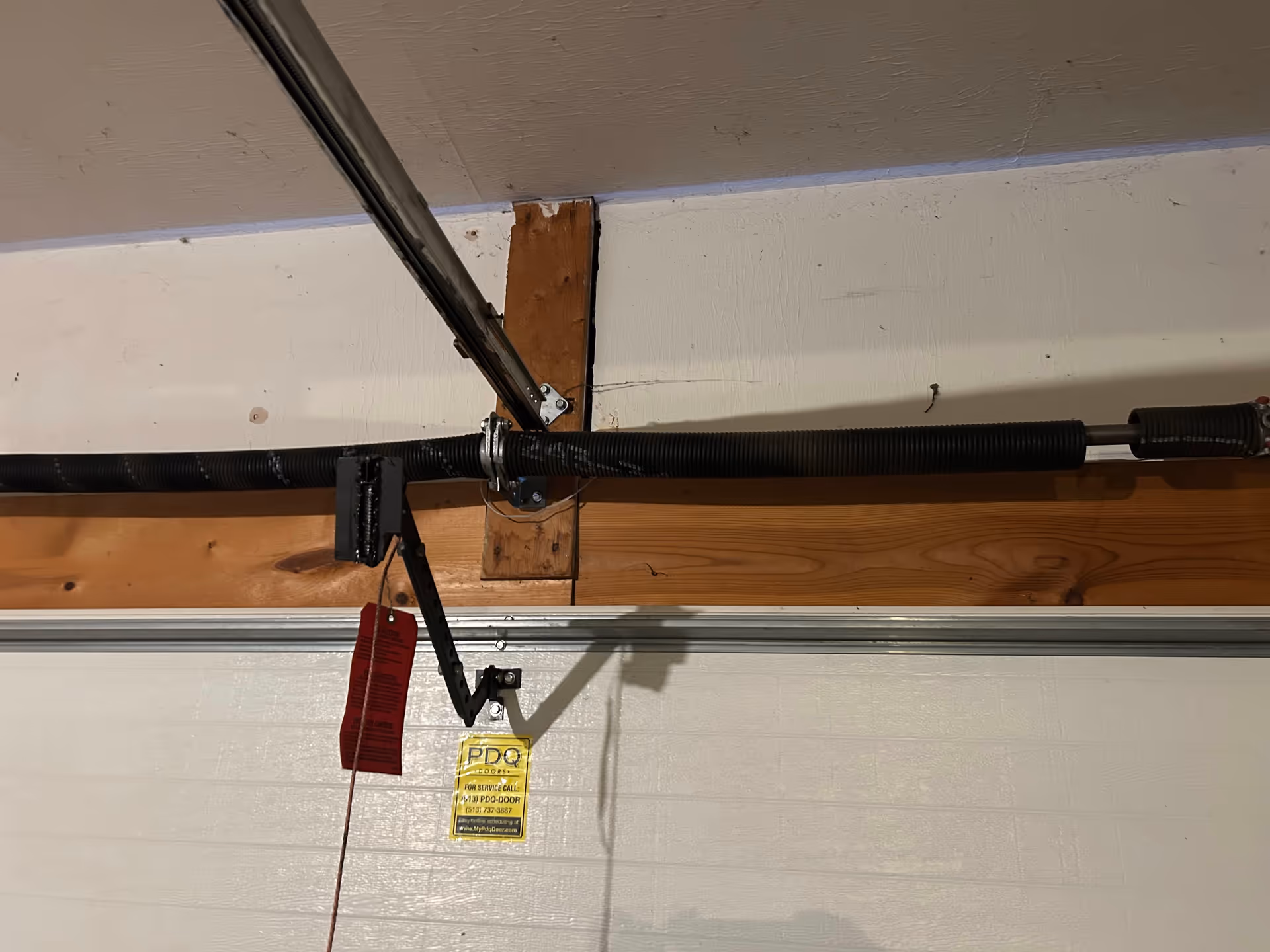 Exposed ceiling with a garage-style door mechanism, cables, and wooden support beam.