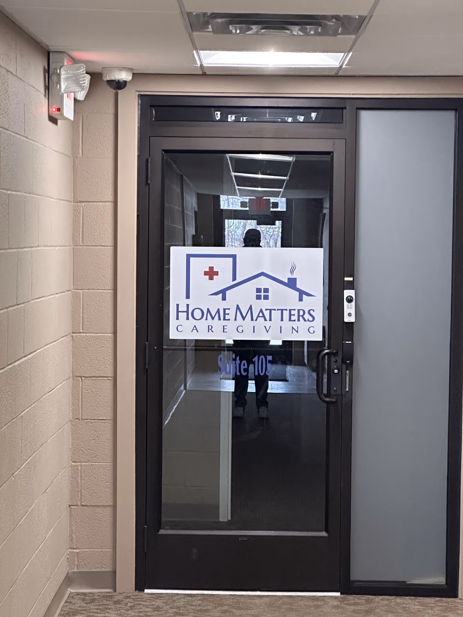 Interior hallway with a glass door displaying the Home Matters Caregiving sign.